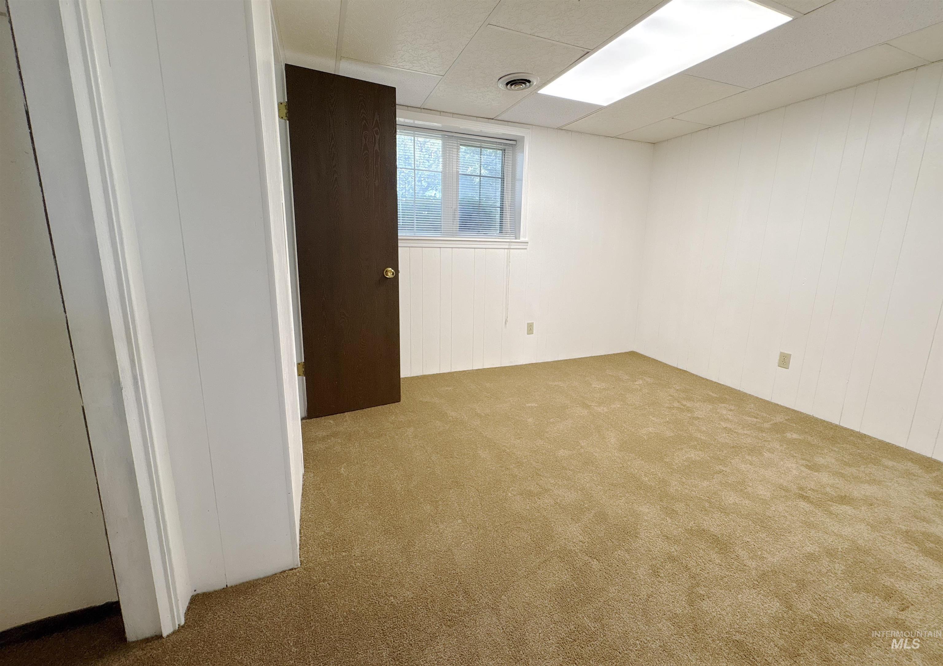 Spare room featuring carpet and a drop ceiling