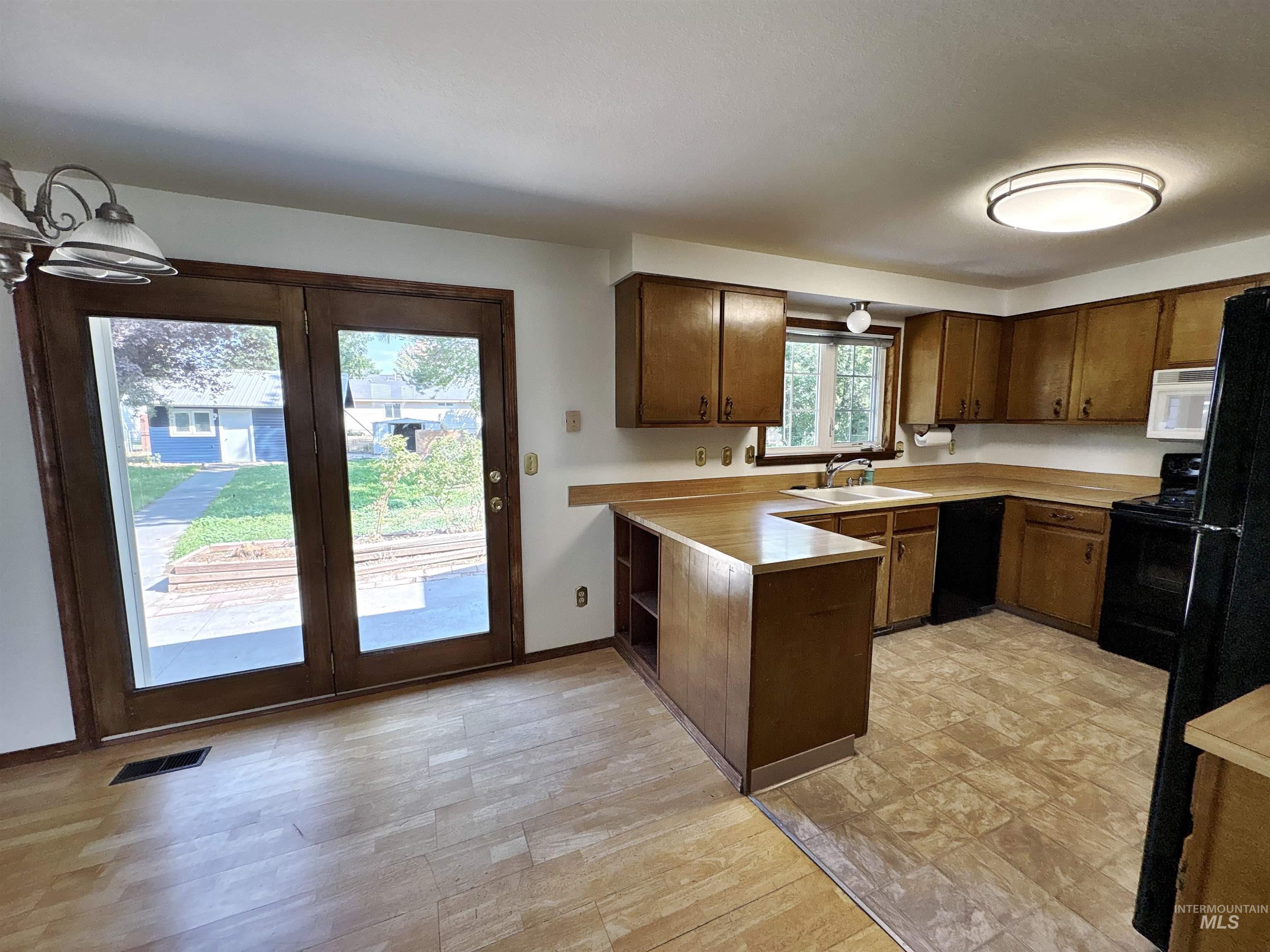 Kitchen featuring black appliances, a peninsula, light countertops, and dark brown cabinets