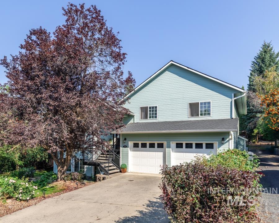 Traditional-style house featuring concrete driveway, an attached garage, and stairs