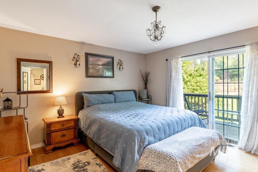 Bedroom featuring wood finished floors, access to exterior, and a chandelier