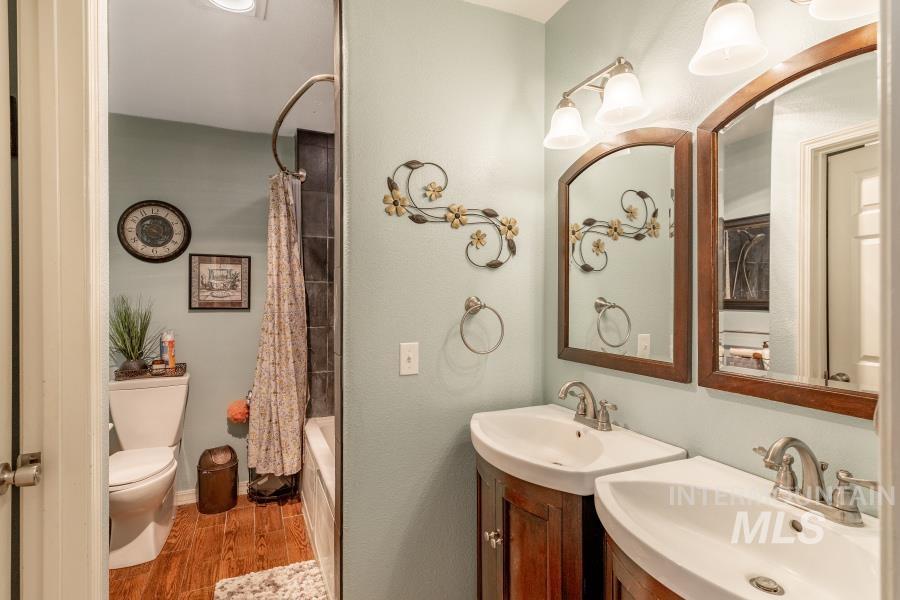 Bathroom featuring shower / bath combo, wood finished floors, and two vanities
