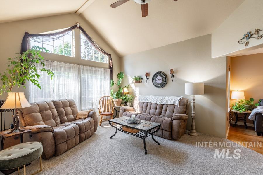 Living room featuring carpet floors, ceiling fan, beam ceiling, and high vaulted ceiling