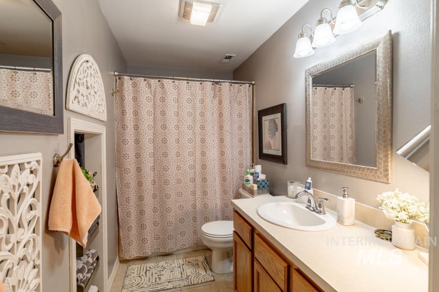 Full bathroom with vanity, light tile patterned floors, and a shower with curtain