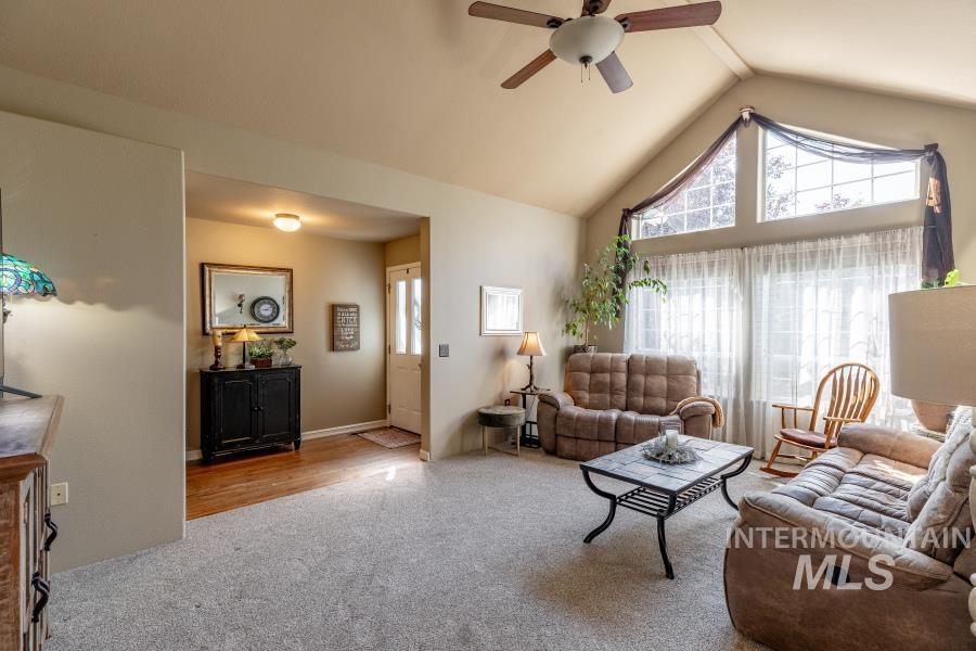 Living room featuring carpet, ceiling fan, and high vaulted ceiling