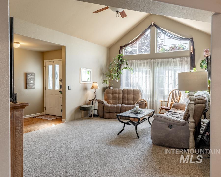 Living room with healthy amount of natural light, carpet floors, lofted ceiling, and a ceiling fan