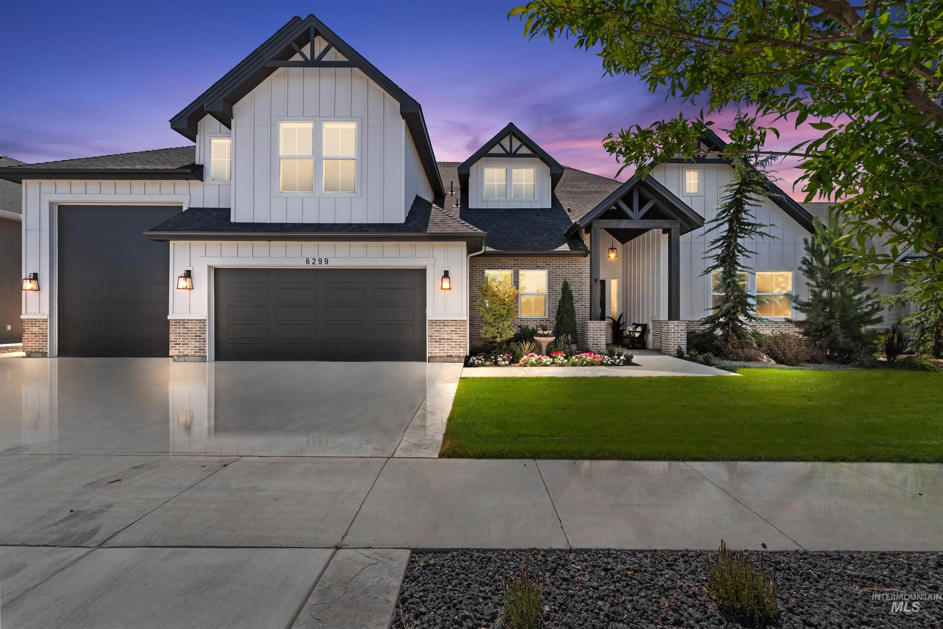 Modern farmhouse with board and batten siding, driveway, a front lawn, and brick siding