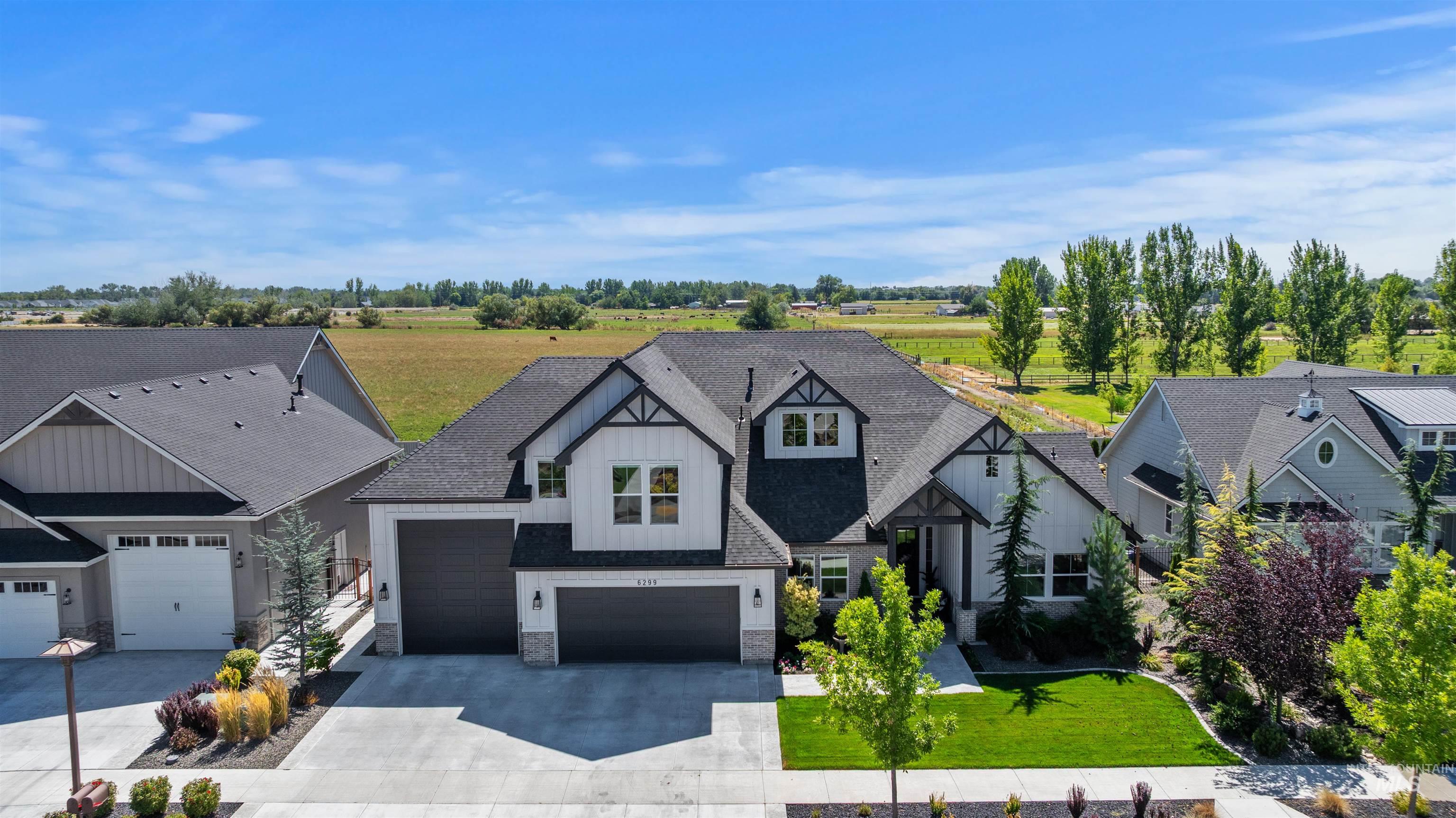 Modern inspired farmhouse featuring board and batten siding, concrete driveway, stone siding, a front yard, and a shingled roof