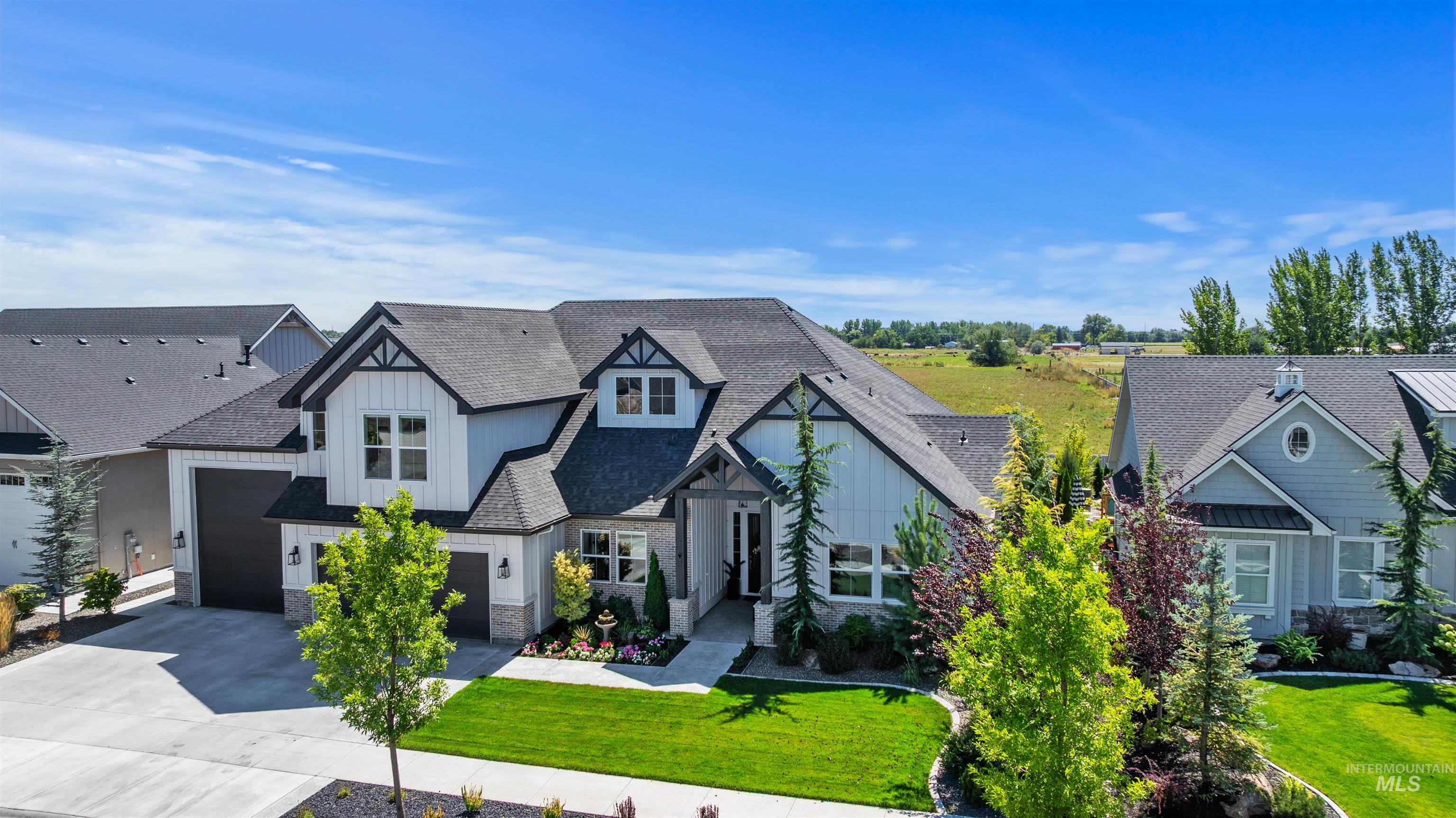 View of front of house with driveway, a front lawn, a shingled roof, board and batten siding, and stone siding