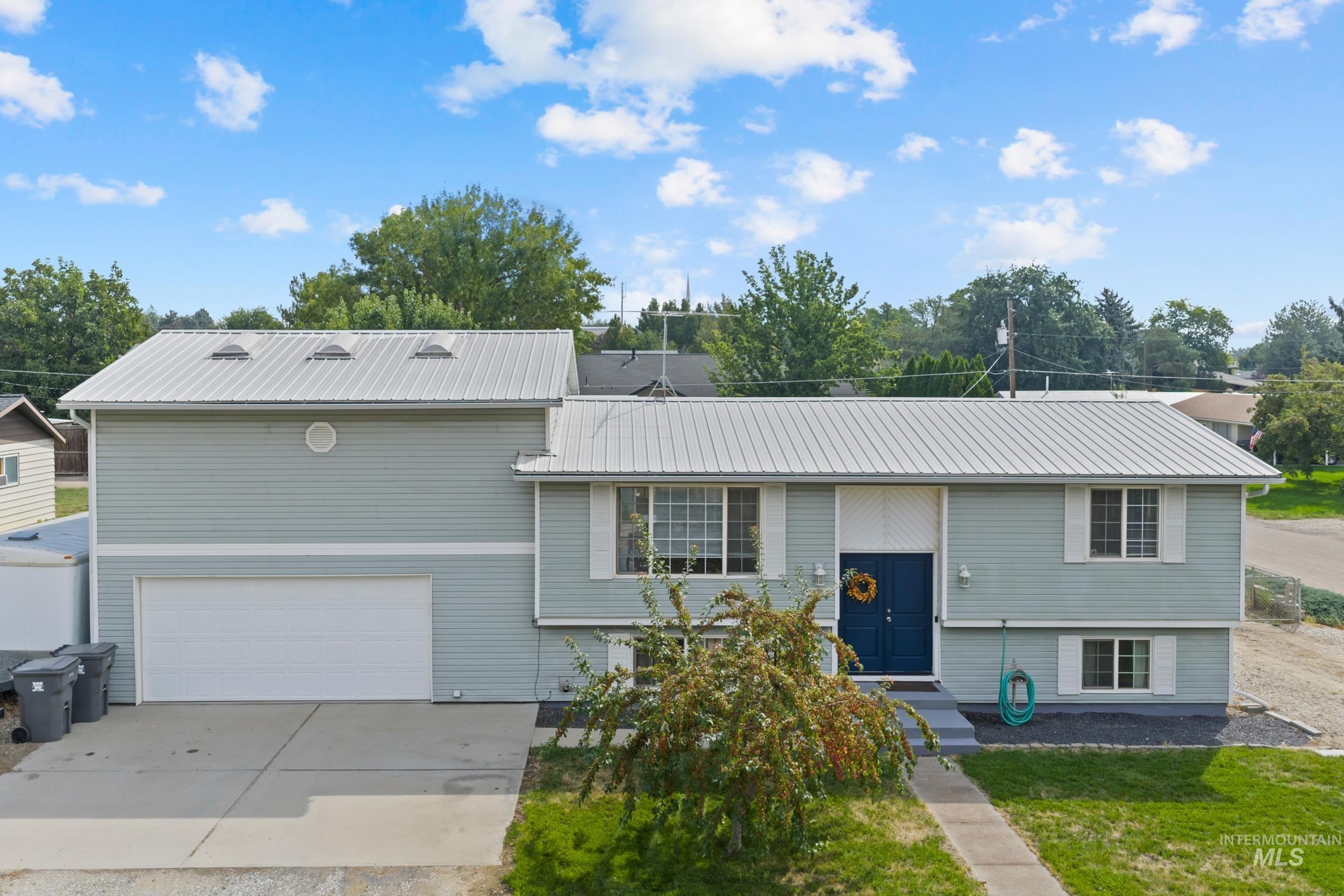 View of front of house with a metal roof, concrete driveway, and a garage