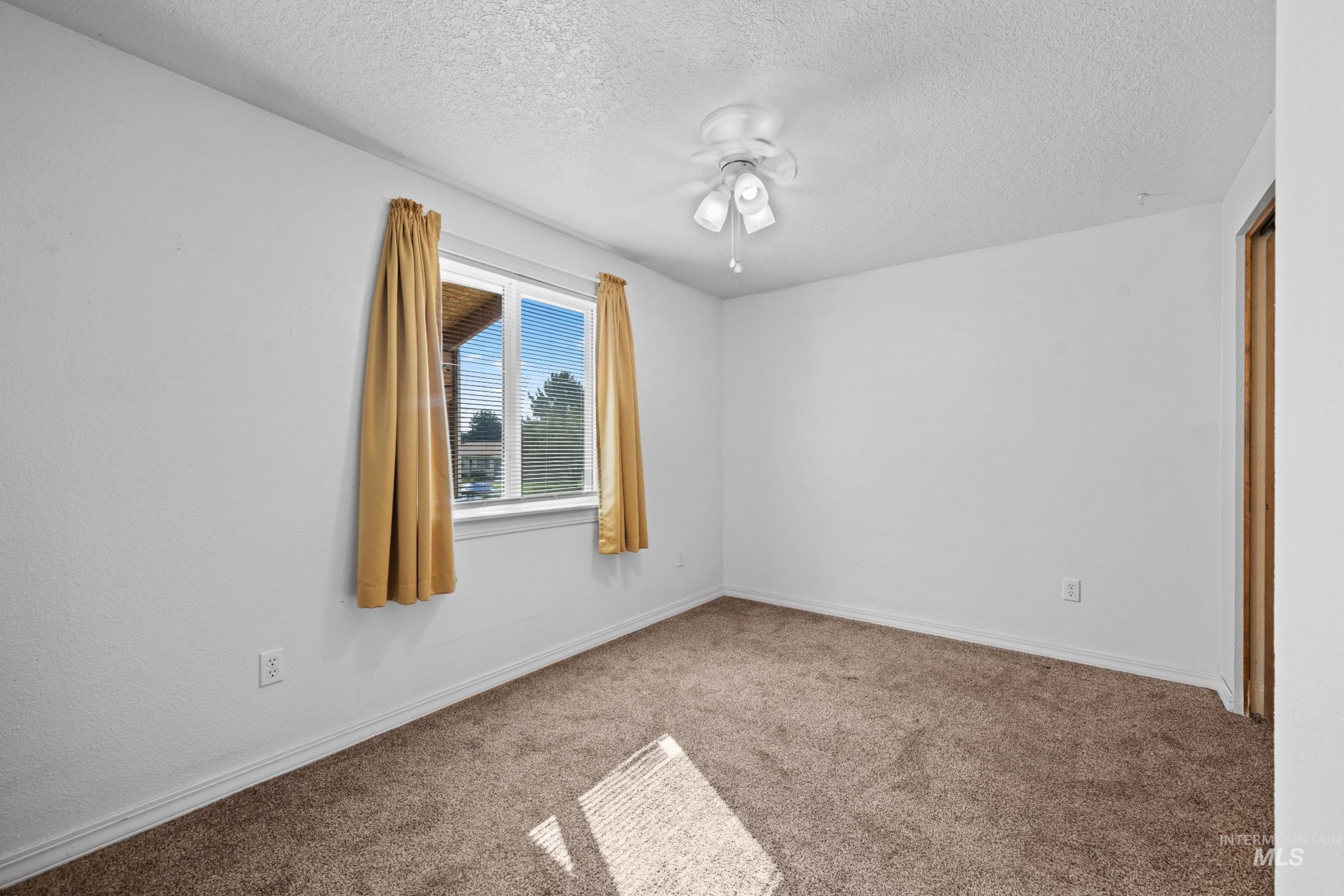 Unfurnished bedroom with carpet, a textured ceiling, and a ceiling fan