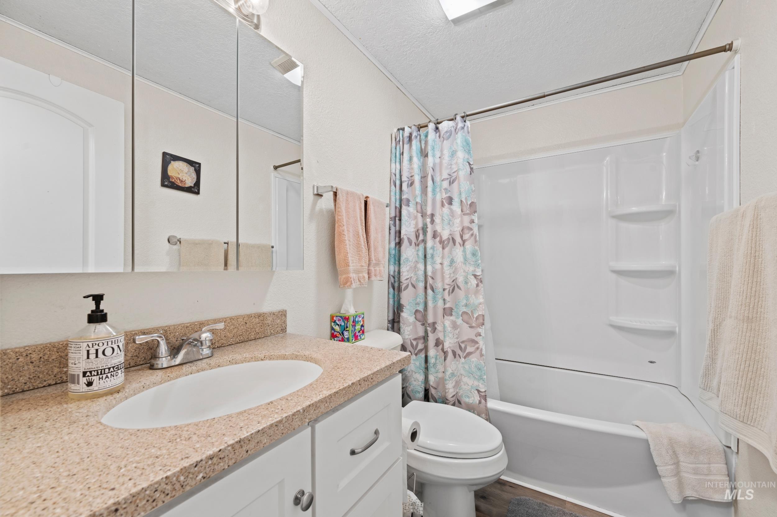 Full bath featuring shower / bath combo with shower curtain, a textured ceiling, and vanity