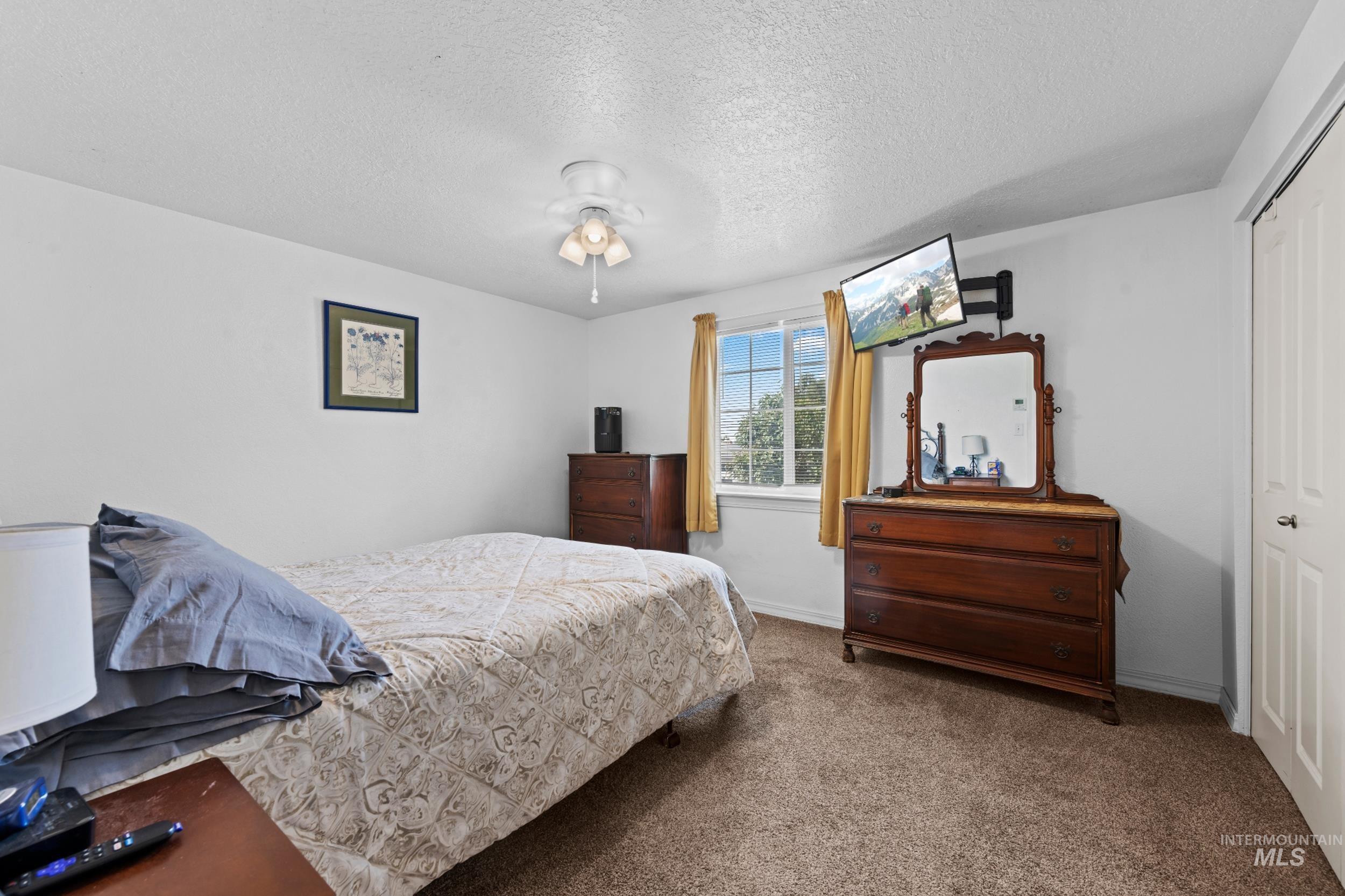 Carpeted bedroom featuring a textured ceiling, a closet, and ceiling fan