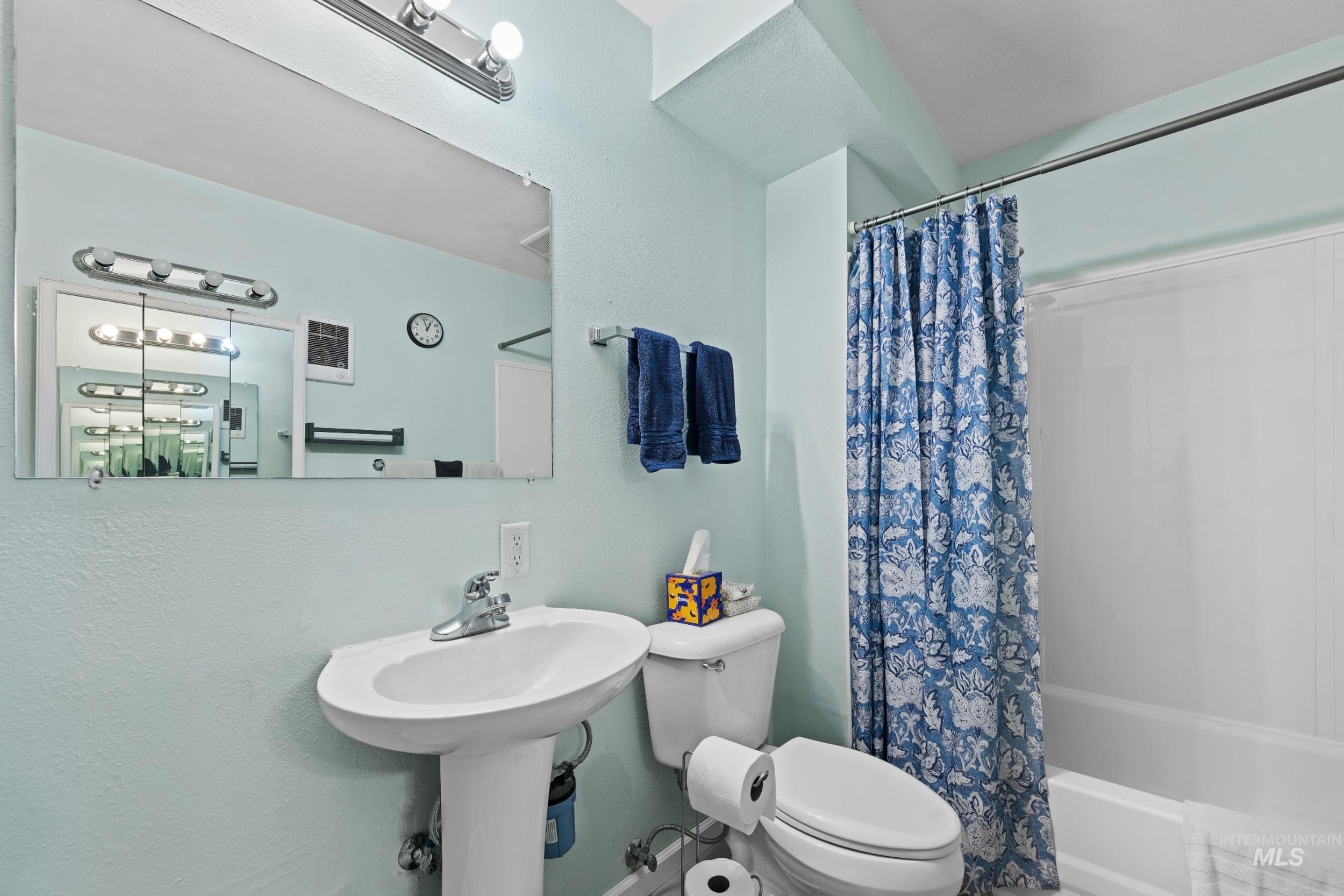 Bathroom featuring toilet and shower / bathtub combination with curtain