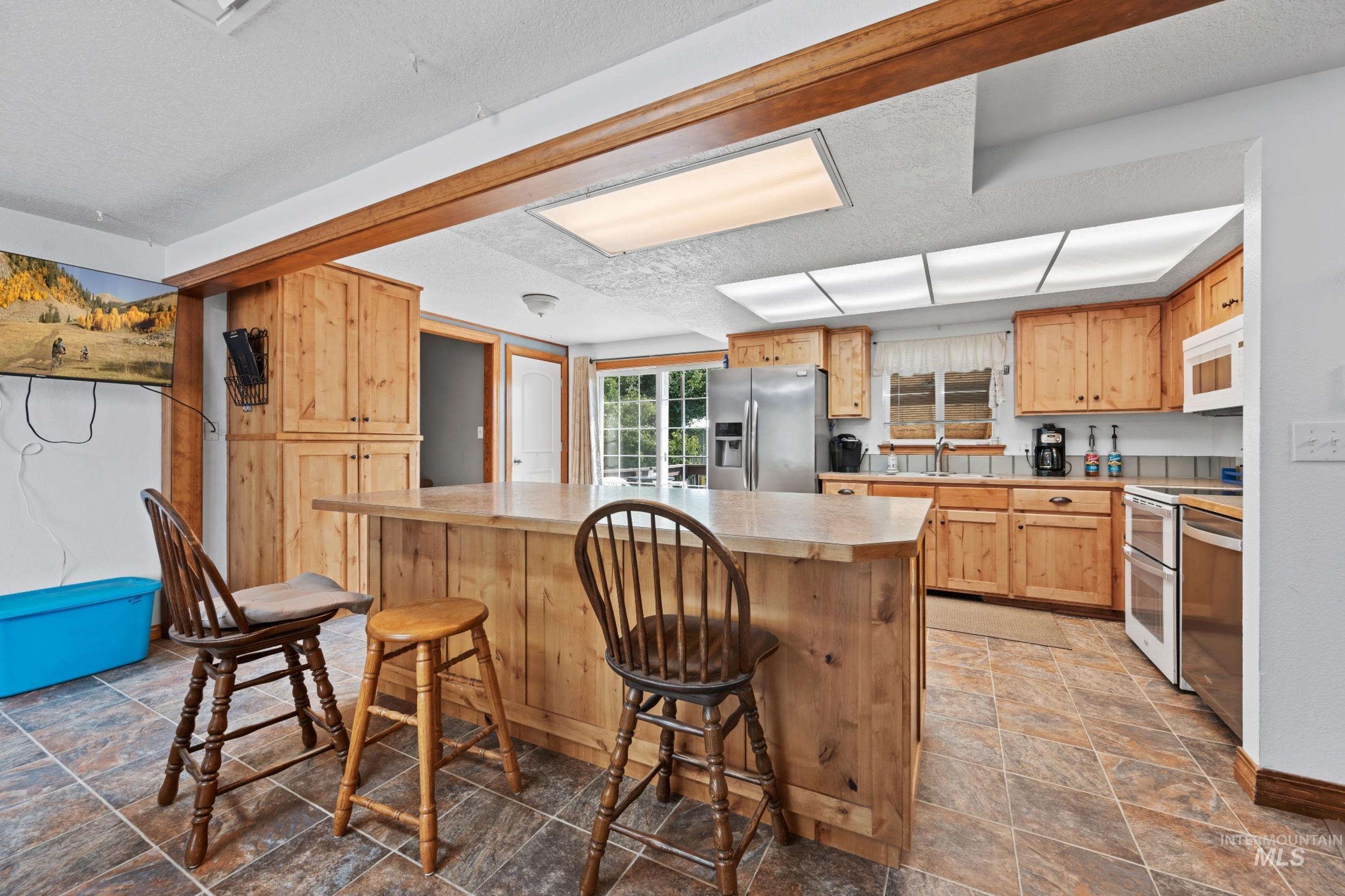 Kitchen featuring light countertops, a breakfast bar area, appliances with stainless steel finishes, and dark stone finish floors