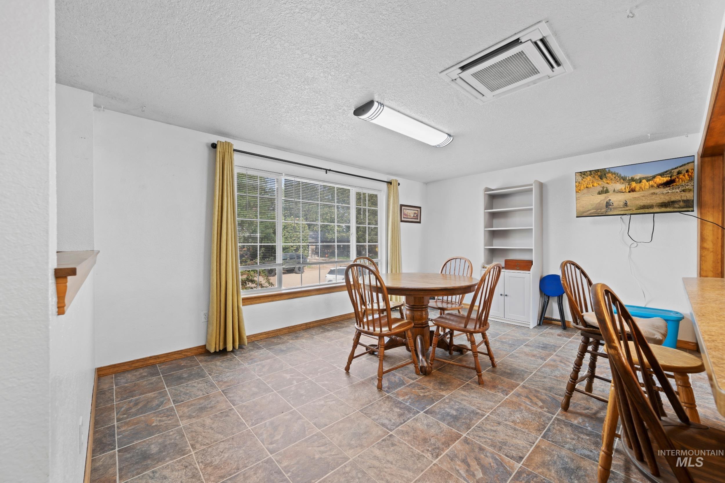 Dining space featuring cooling unit, stone finish floors, and a textured ceiling