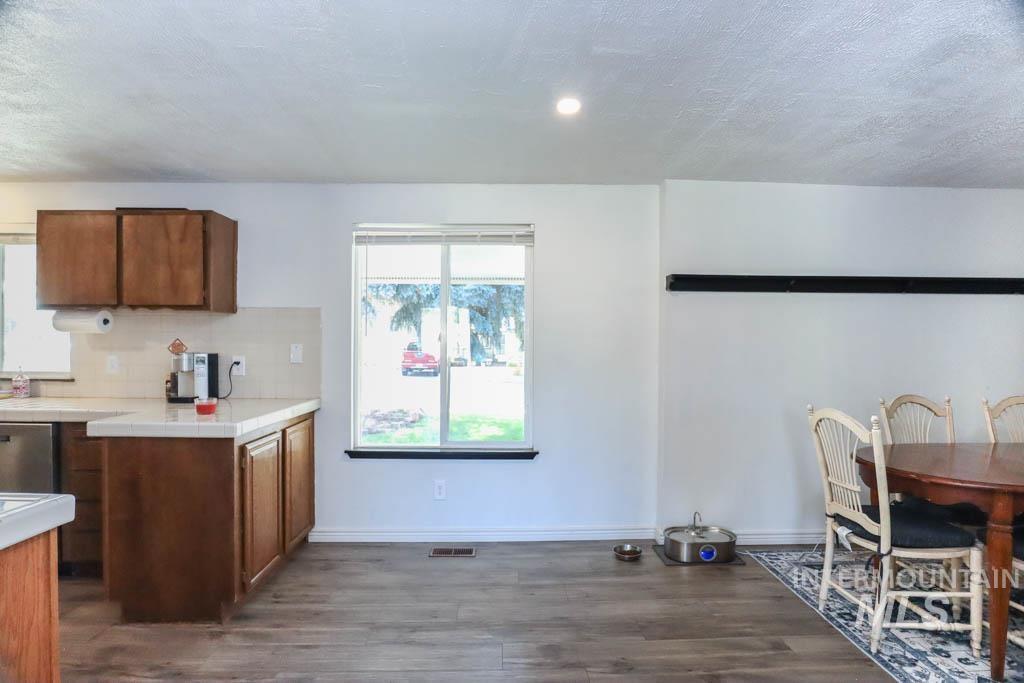 Kitchen featuring brown cabinetry, a textured ceiling, dark wood-style flooring, and backsplash