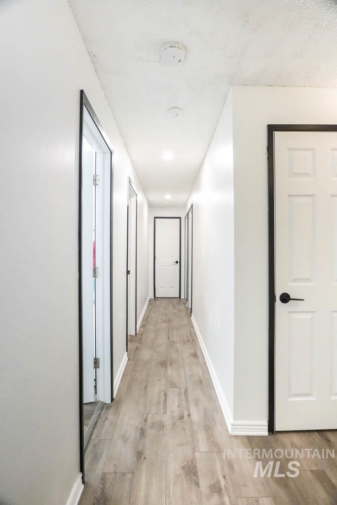 Hallway with light wood-type flooring and baseboards