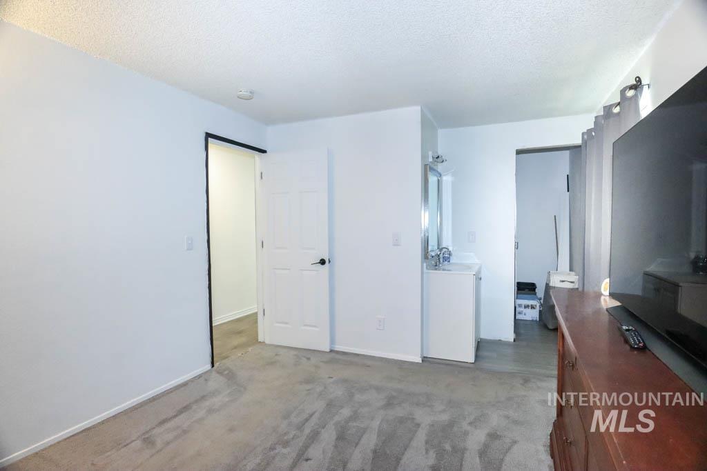 Bedroom with light colored carpet and a textured ceiling