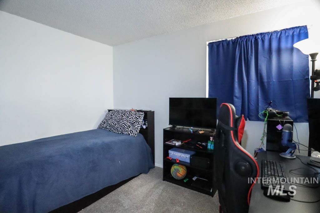 Carpeted bedroom with a textured ceiling and an office area