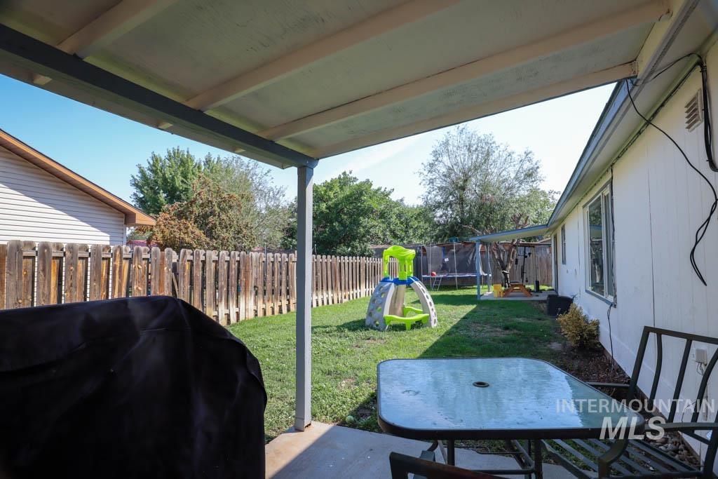 Fenced backyard featuring outdoor dining space, a patio, a trampoline, and a playground