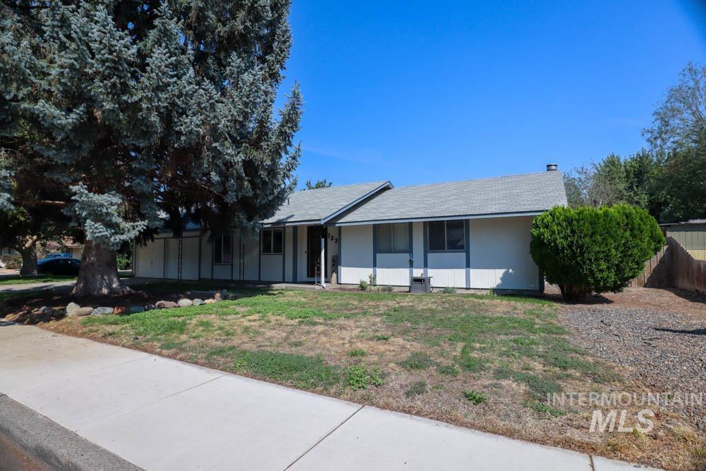 Ranch-style home featuring a shingled roof and a front yard