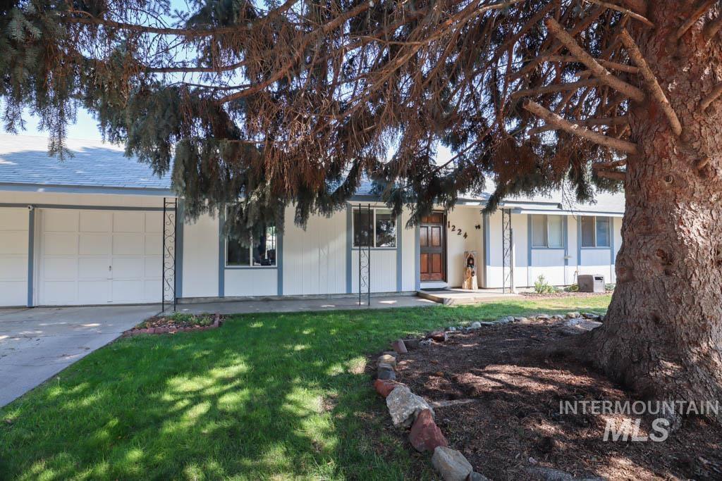 Ranch-style house featuring a front yard, a garage, and driveway