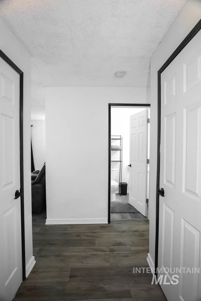 Hall with a textured ceiling and dark wood-style flooring