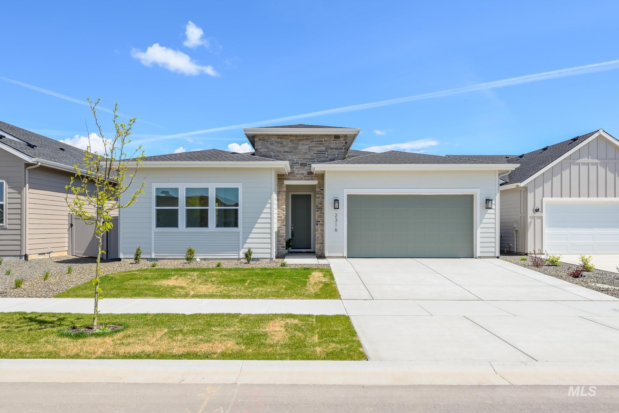 View of front facade with an attached garage, driveway, stone siding, and roof with shingles