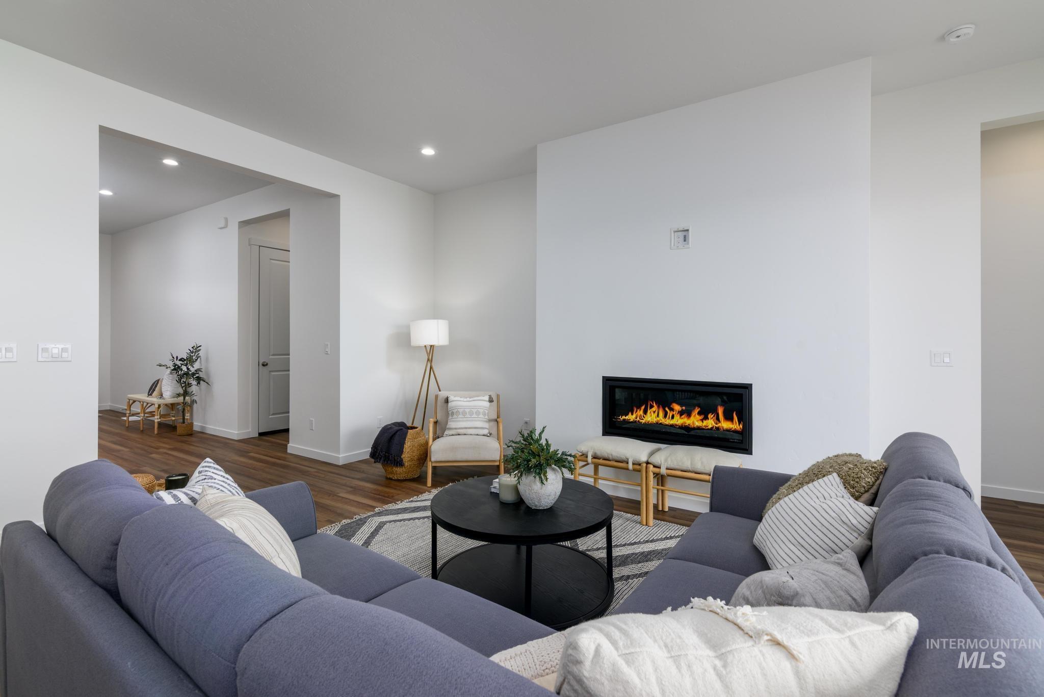 Living area featuring a glass covered fireplace, wood finished floors, and recessed lighting