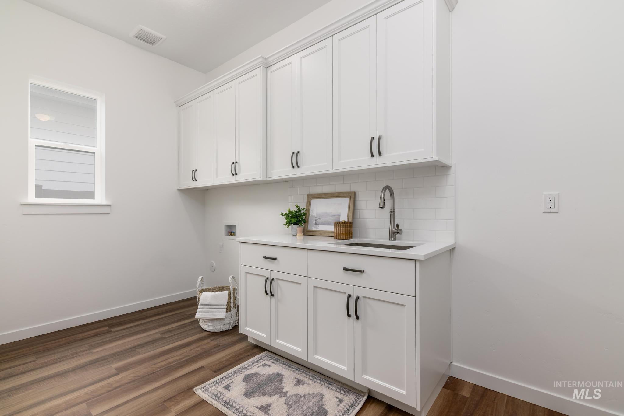 Washroom featuring washer hookup, dark wood-style flooring, and cabinet space