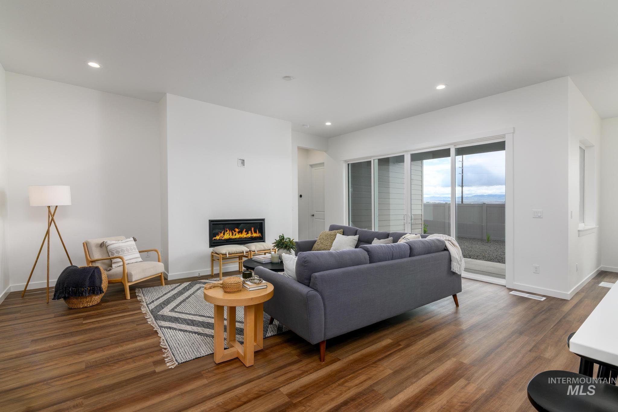 Living area with recessed lighting, a glass covered fireplace, and dark wood-style floors