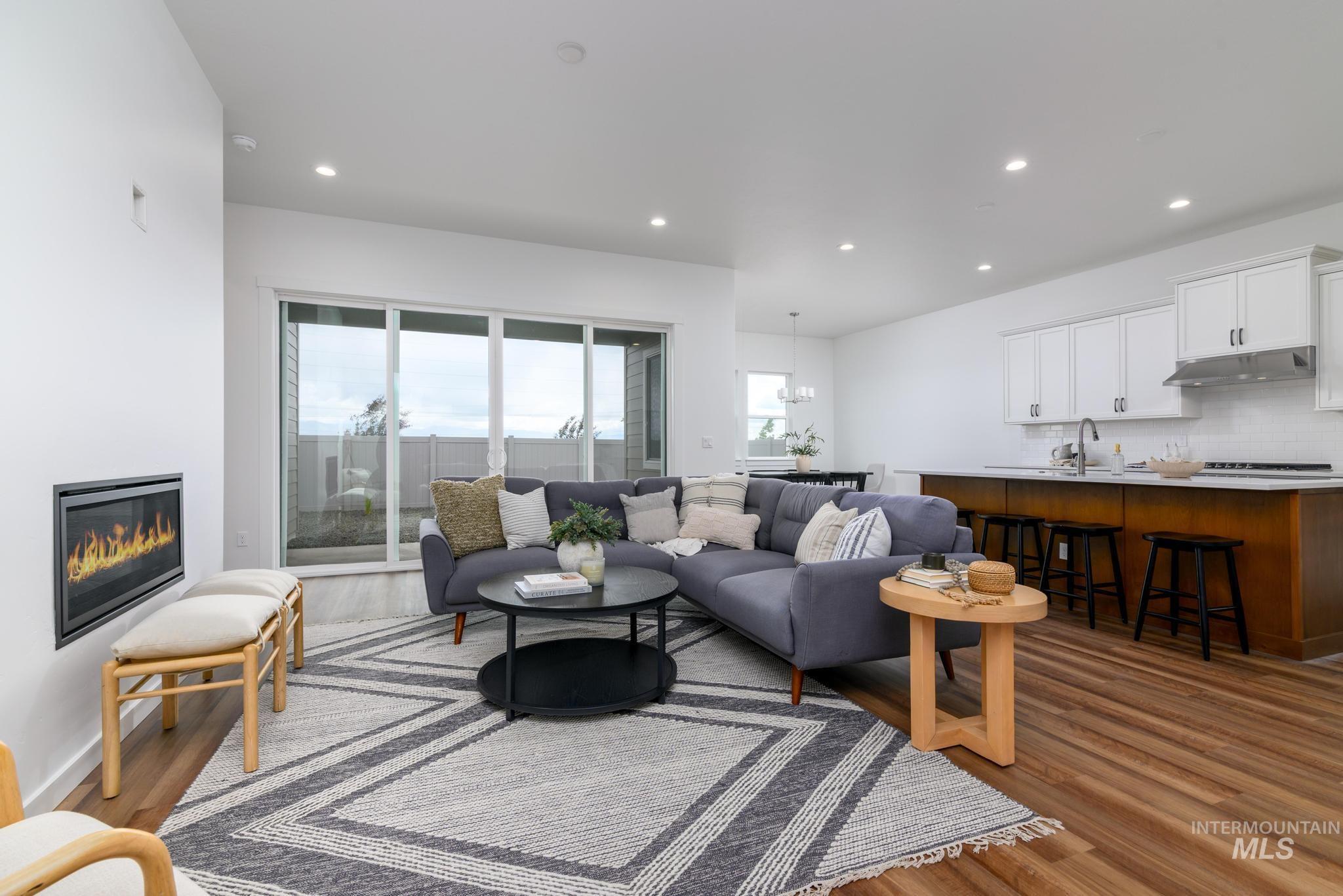 Living room featuring a glass covered fireplace, recessed lighting, dark wood-type flooring, and a chandelier