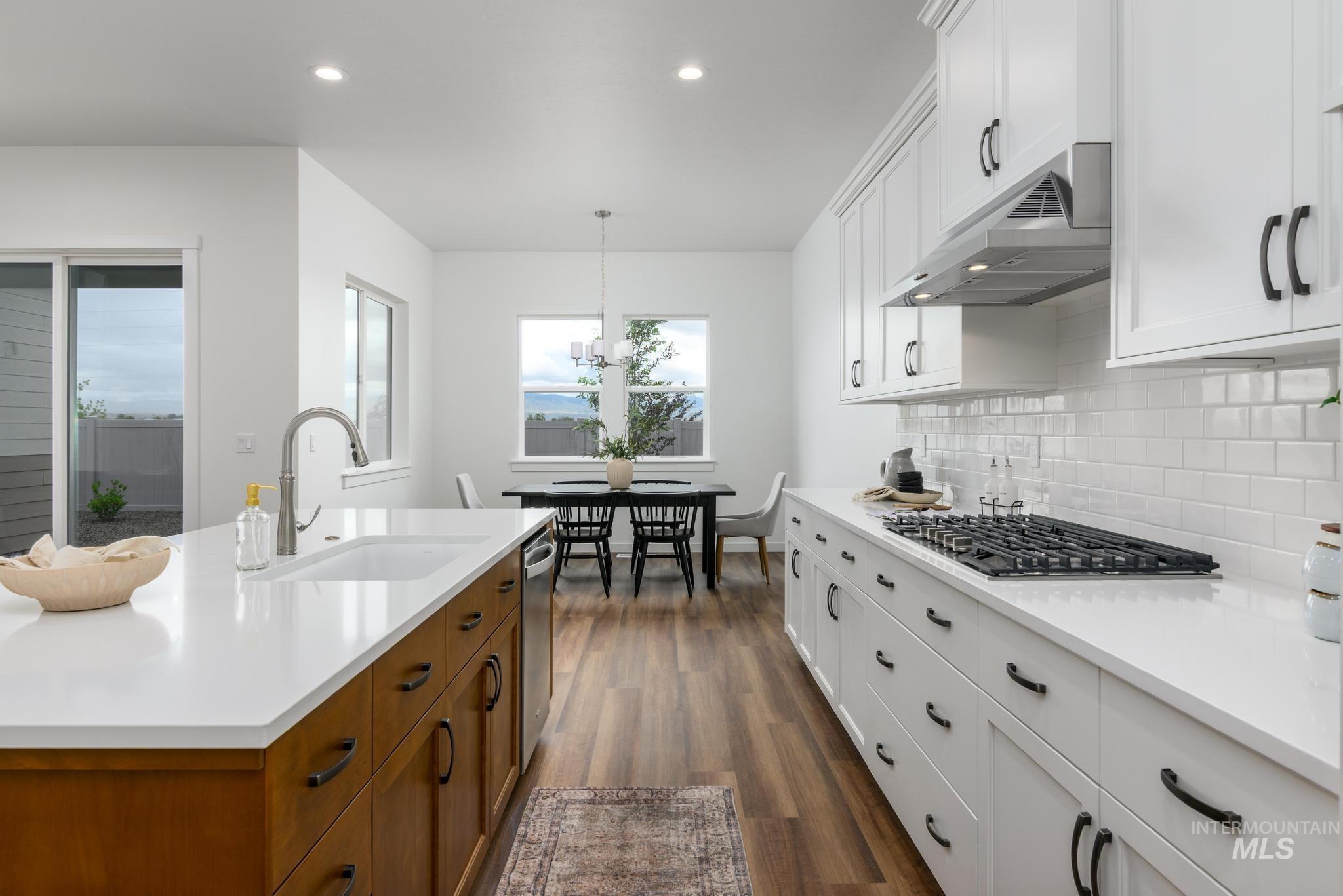 Kitchen with white cabinets, brown cabinetry, hanging light fixtures, dark wood finished floors, and recessed lighting