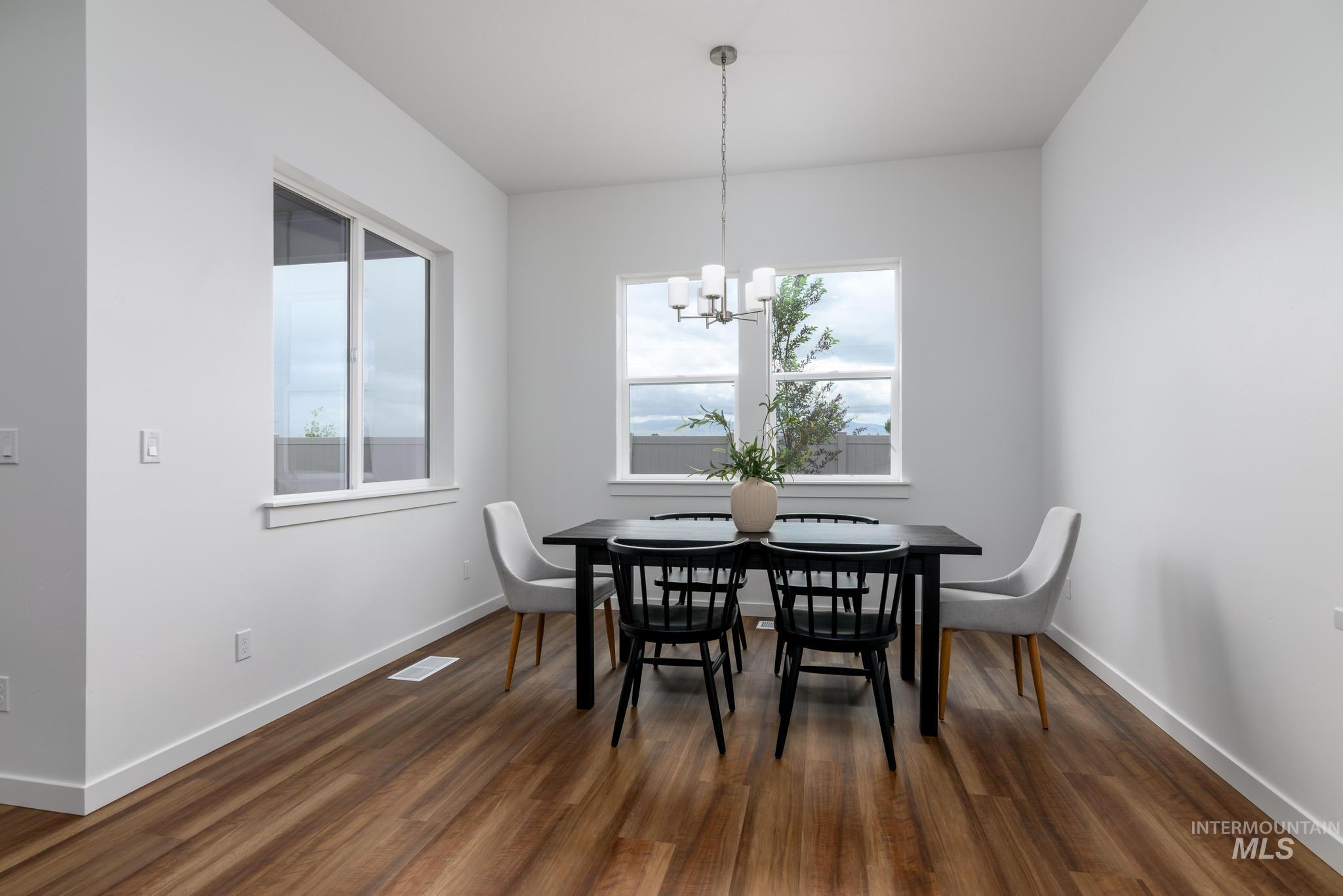 Dining space featuring dark wood-style flooring and a chandelier