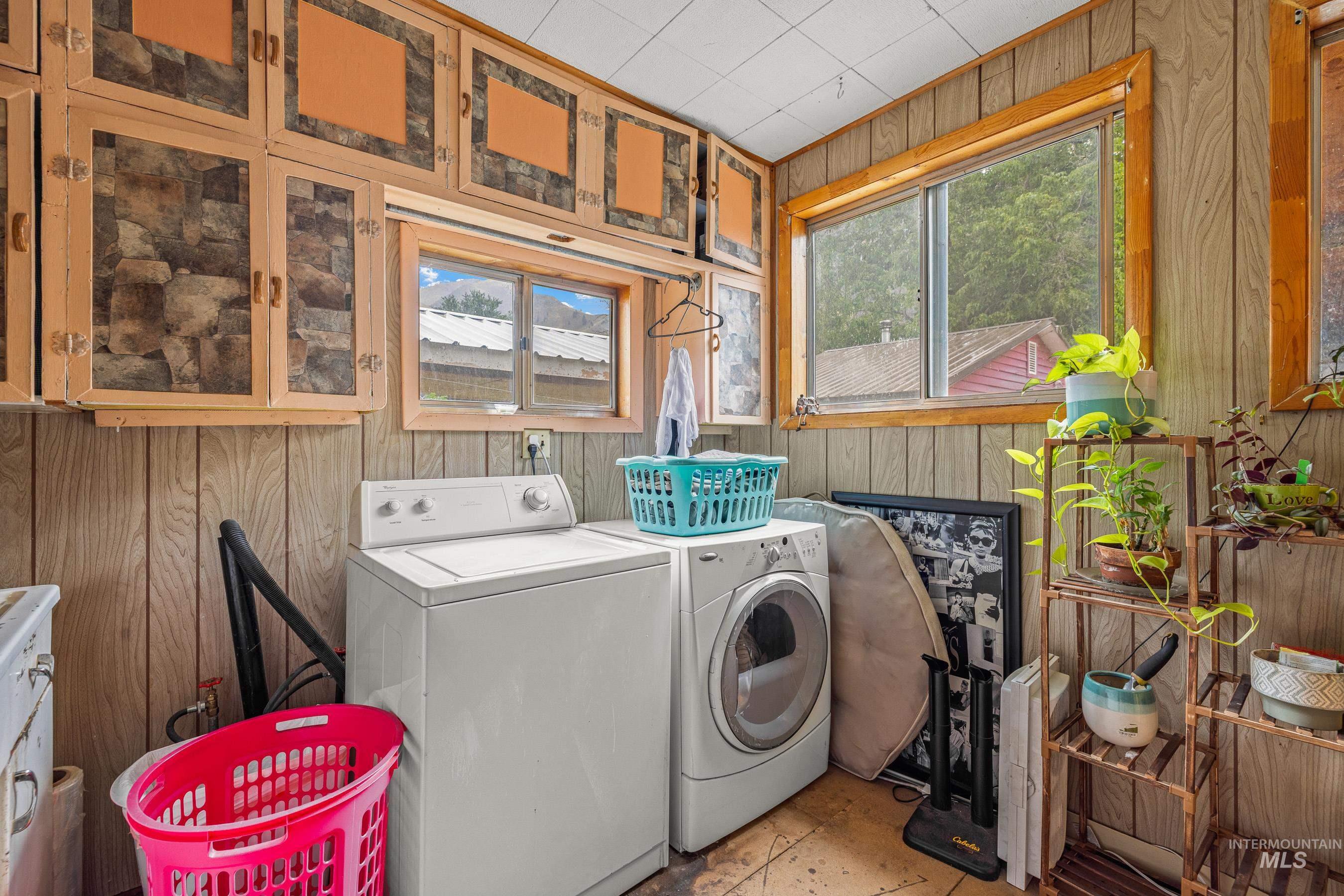 Laundry room featuring wood walls and washing machine and dryer