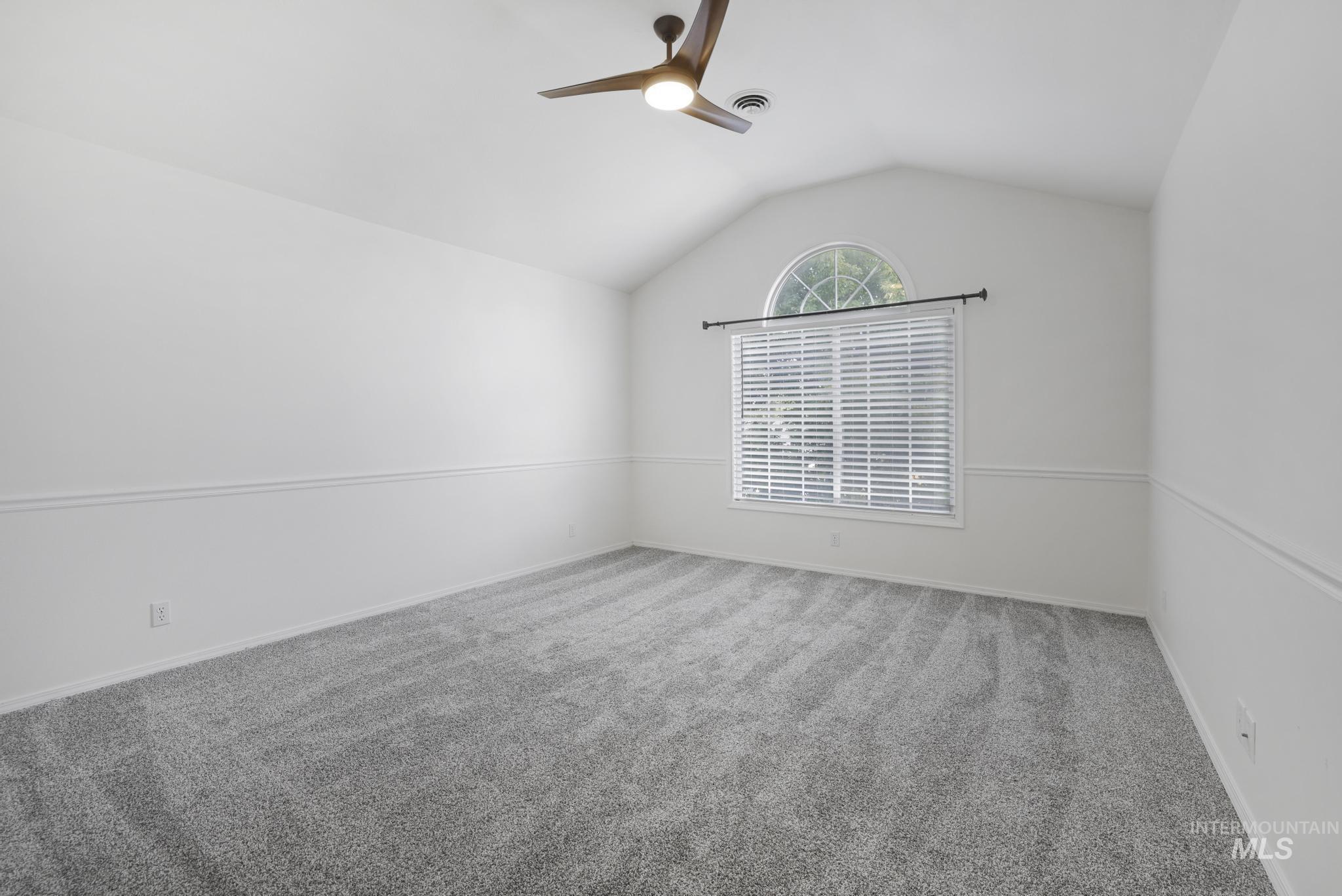 Unfurnished room with lofted ceiling, carpet, and a ceiling fan