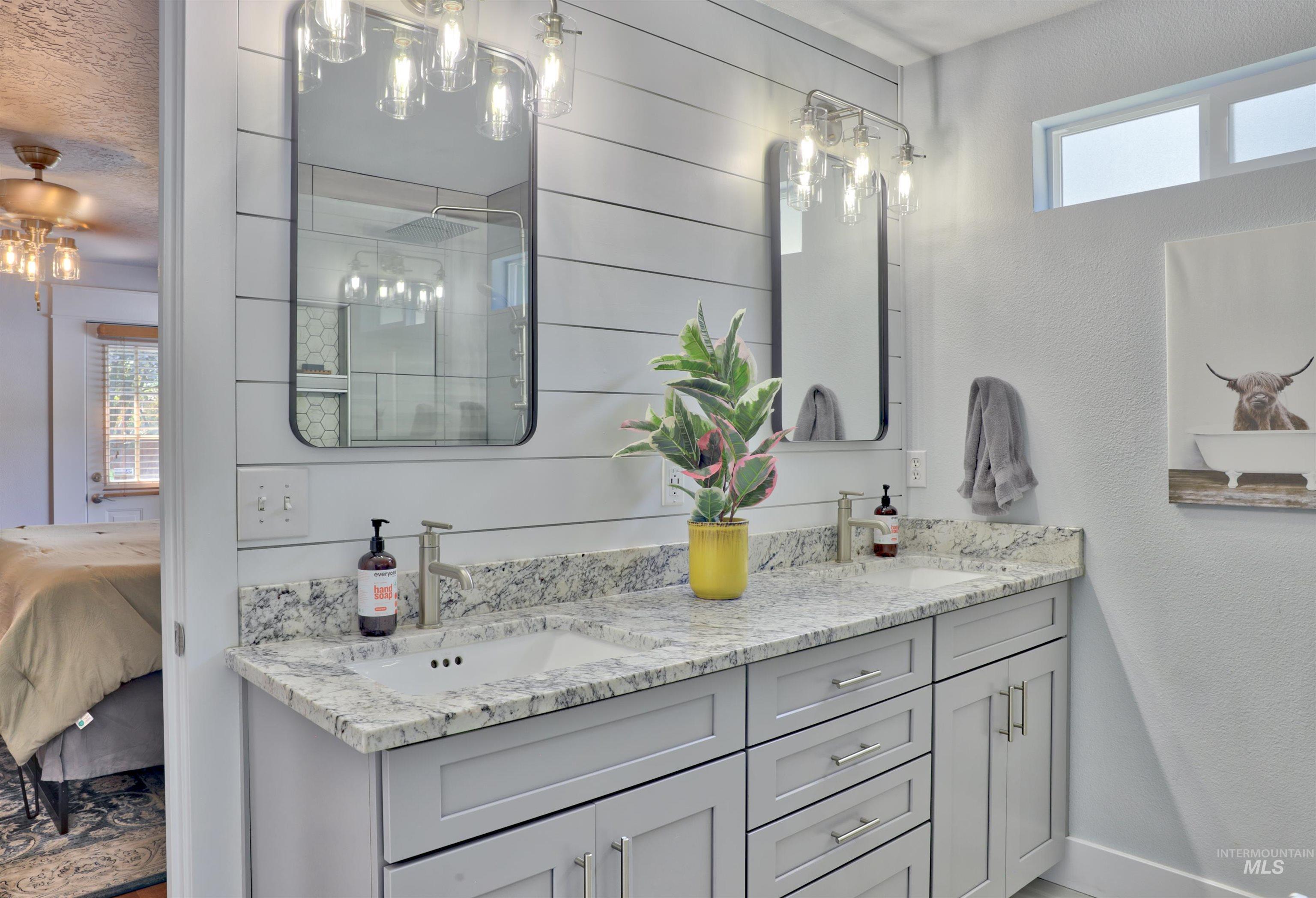 Bathroom with double vanity, a stall shower, ensuite bathroom, and a textured wall