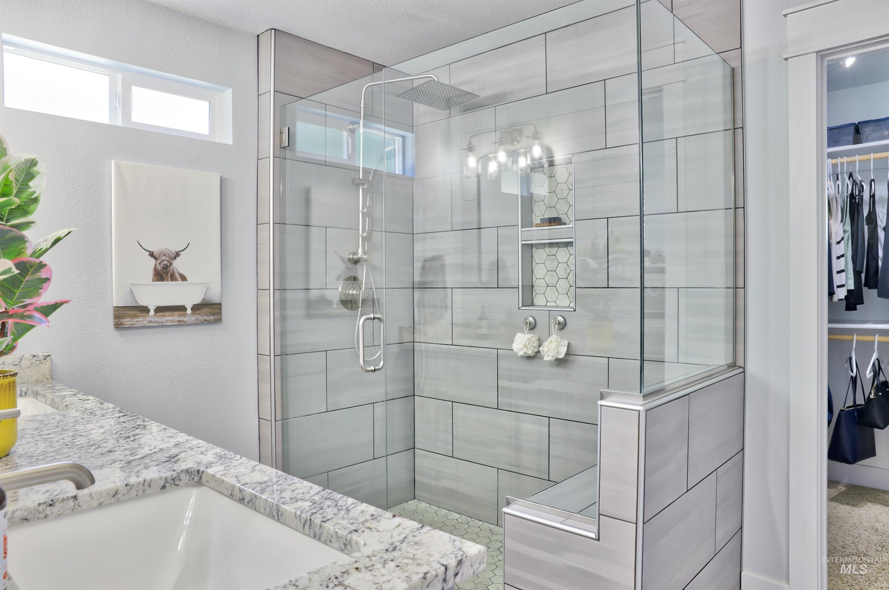 Full bath featuring a walk in closet, a walk in shower, and double vanity