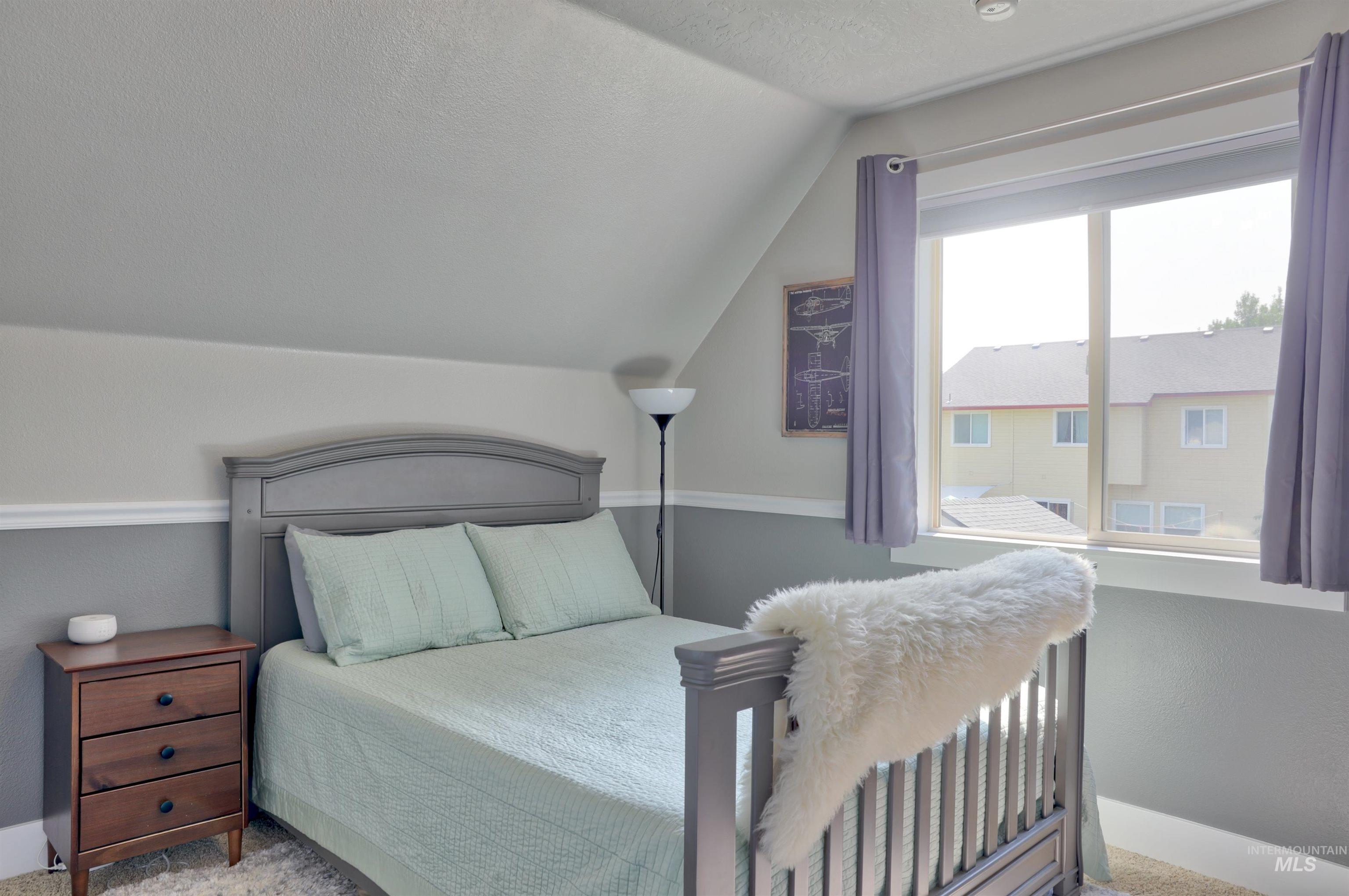 Carpeted bedroom with a textured ceiling and lofted ceiling