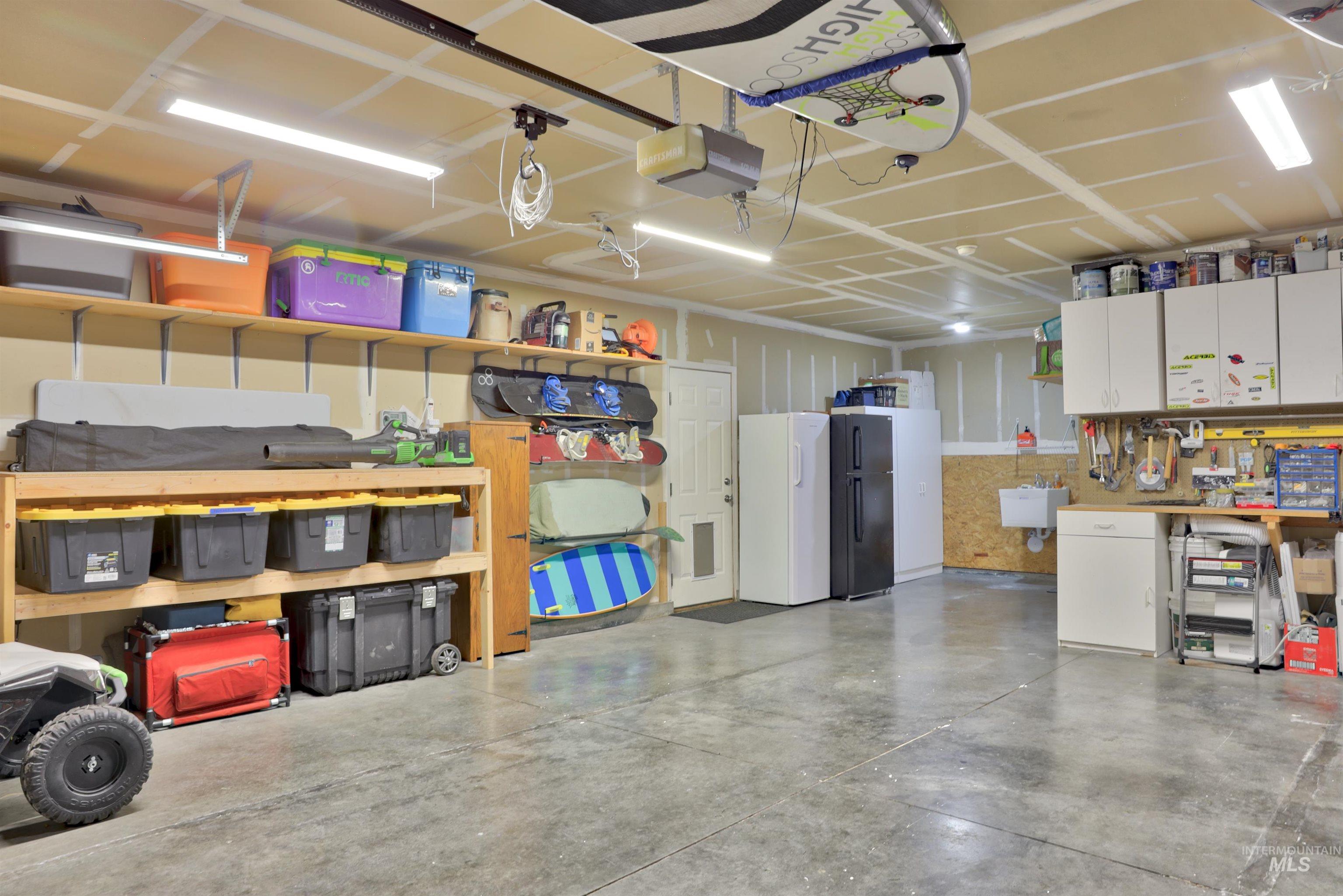 Garage with freestanding refrigerator, a workshop area, and a garage door opener