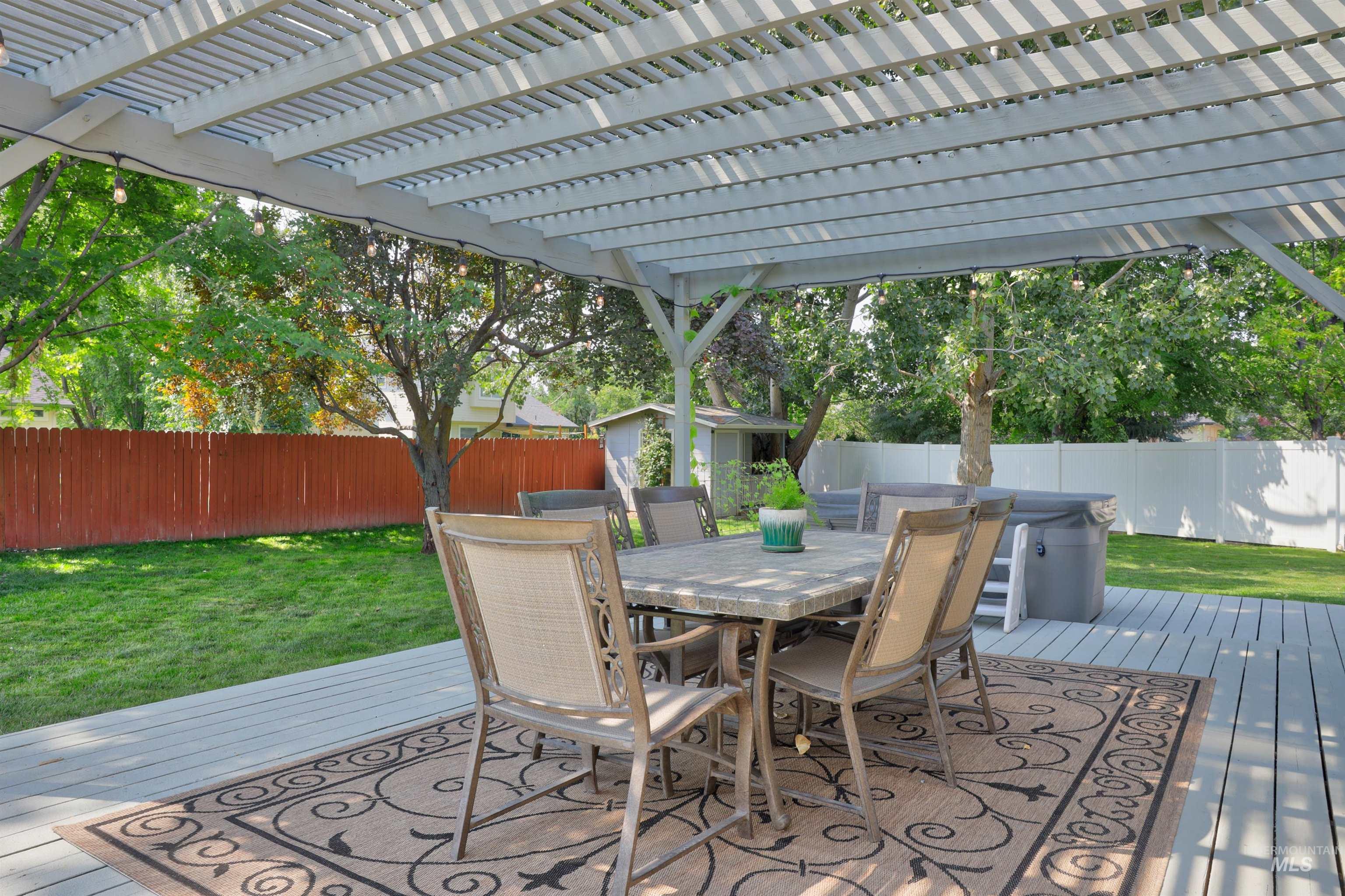 Deck with a fenced backyard, outdoor dining area, and a storage unit