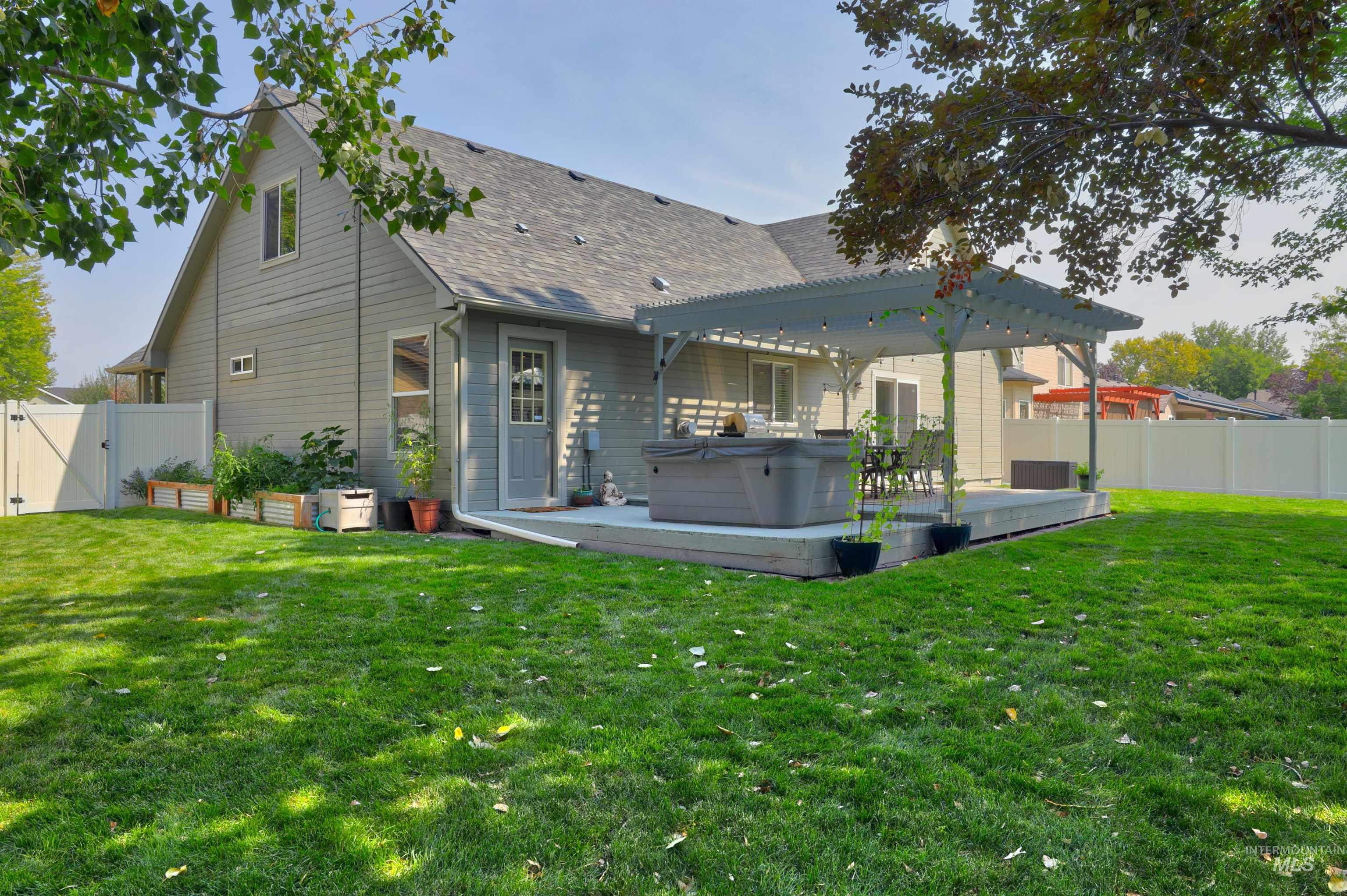 Back of house featuring a gate, a fenced backyard, a hot tub, and a wooden deck