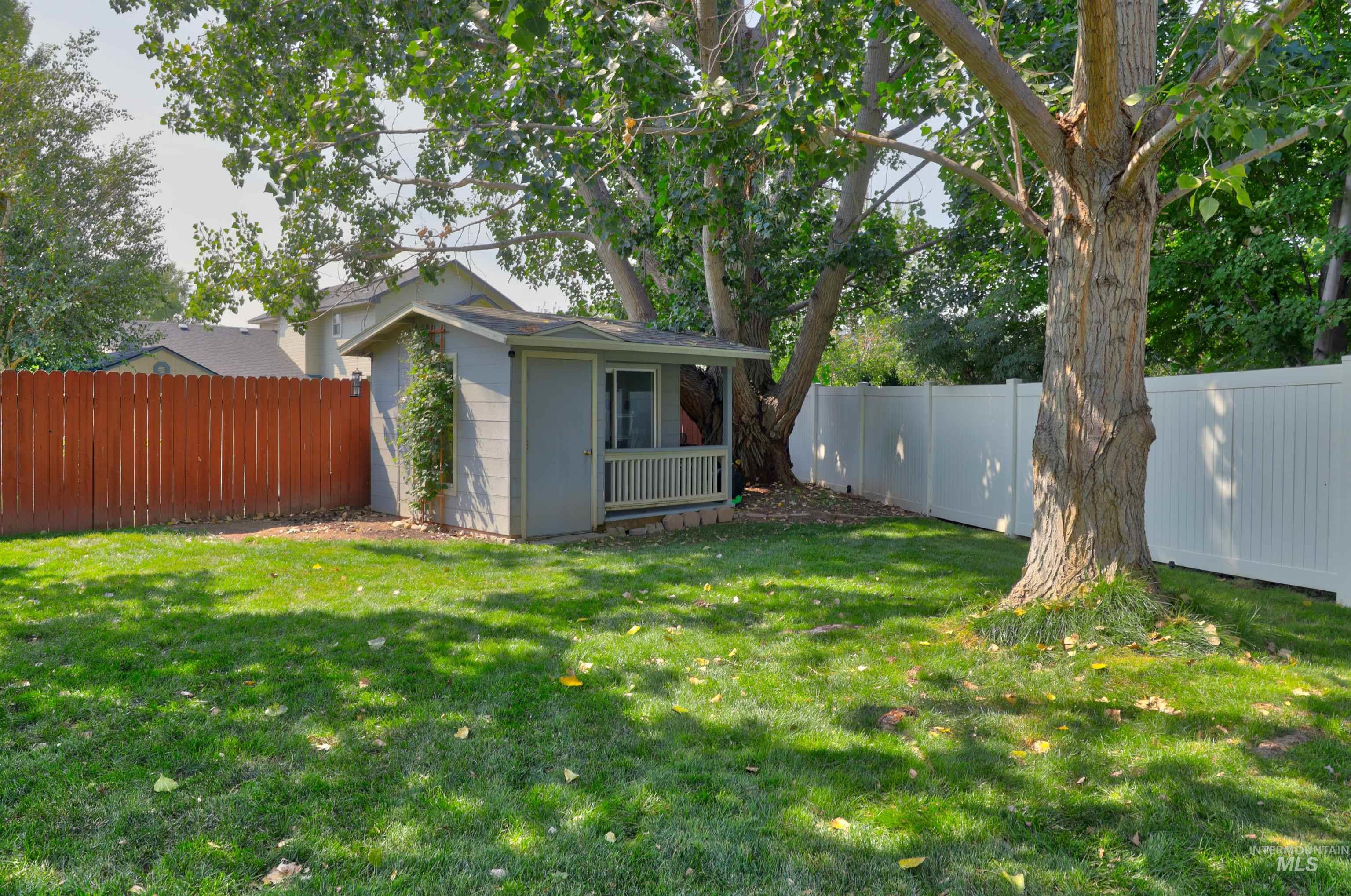Fenced backyard featuring an outbuilding