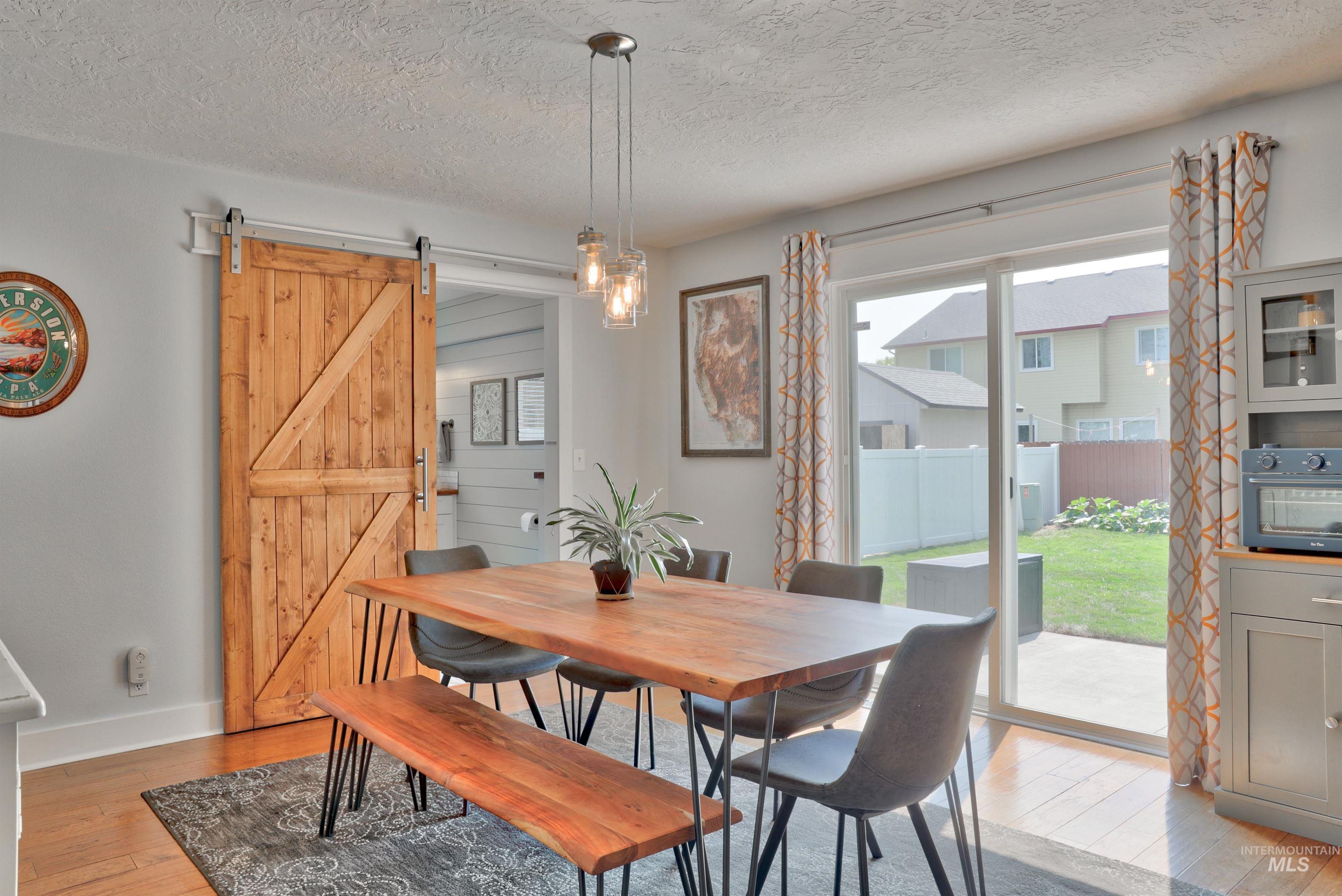 Dining area with light wood-style flooring, a barn door, and a textured ceiling