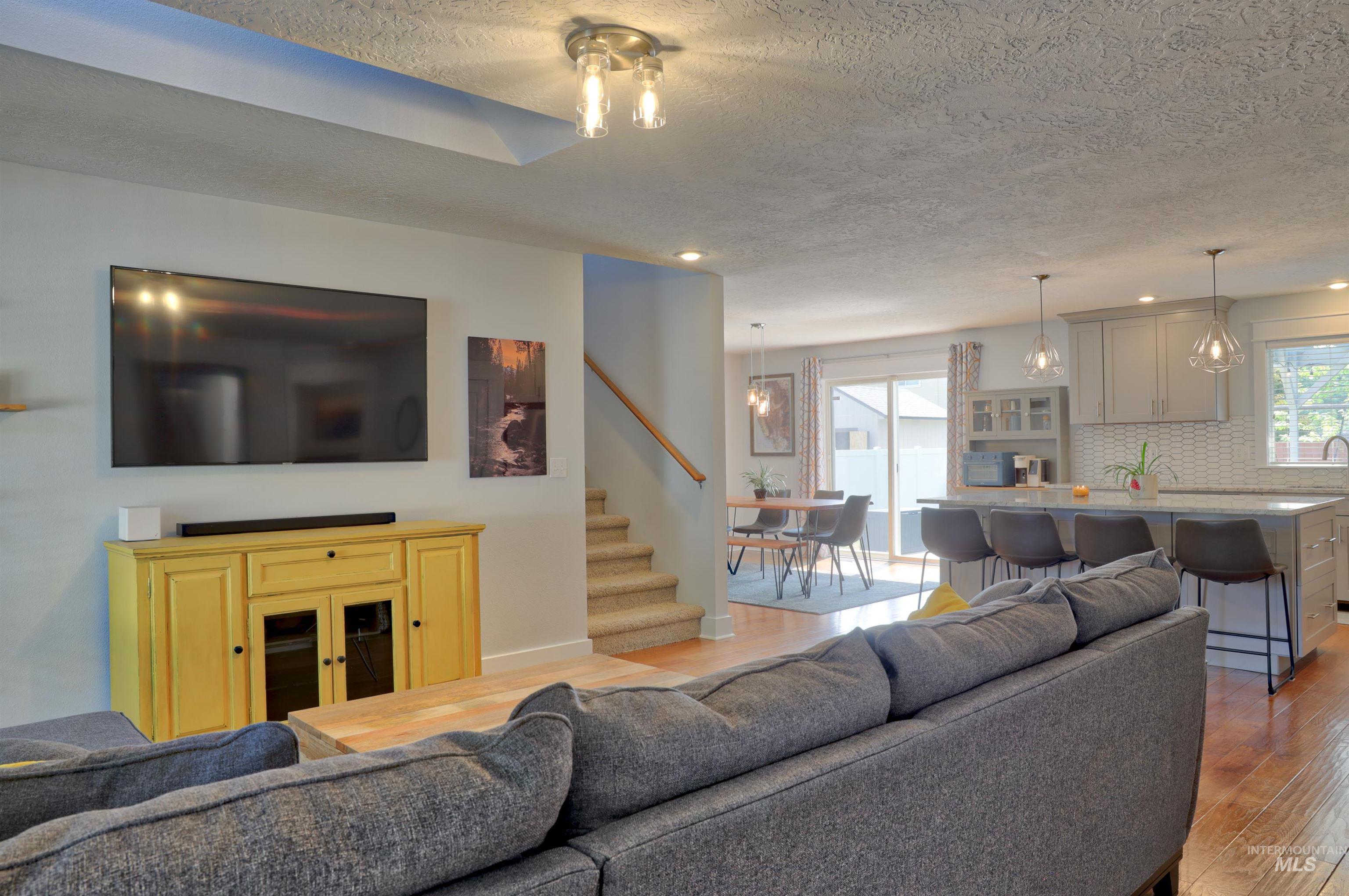 Living area featuring light wood finished floors, a textured ceiling, stairs, and recessed lighting