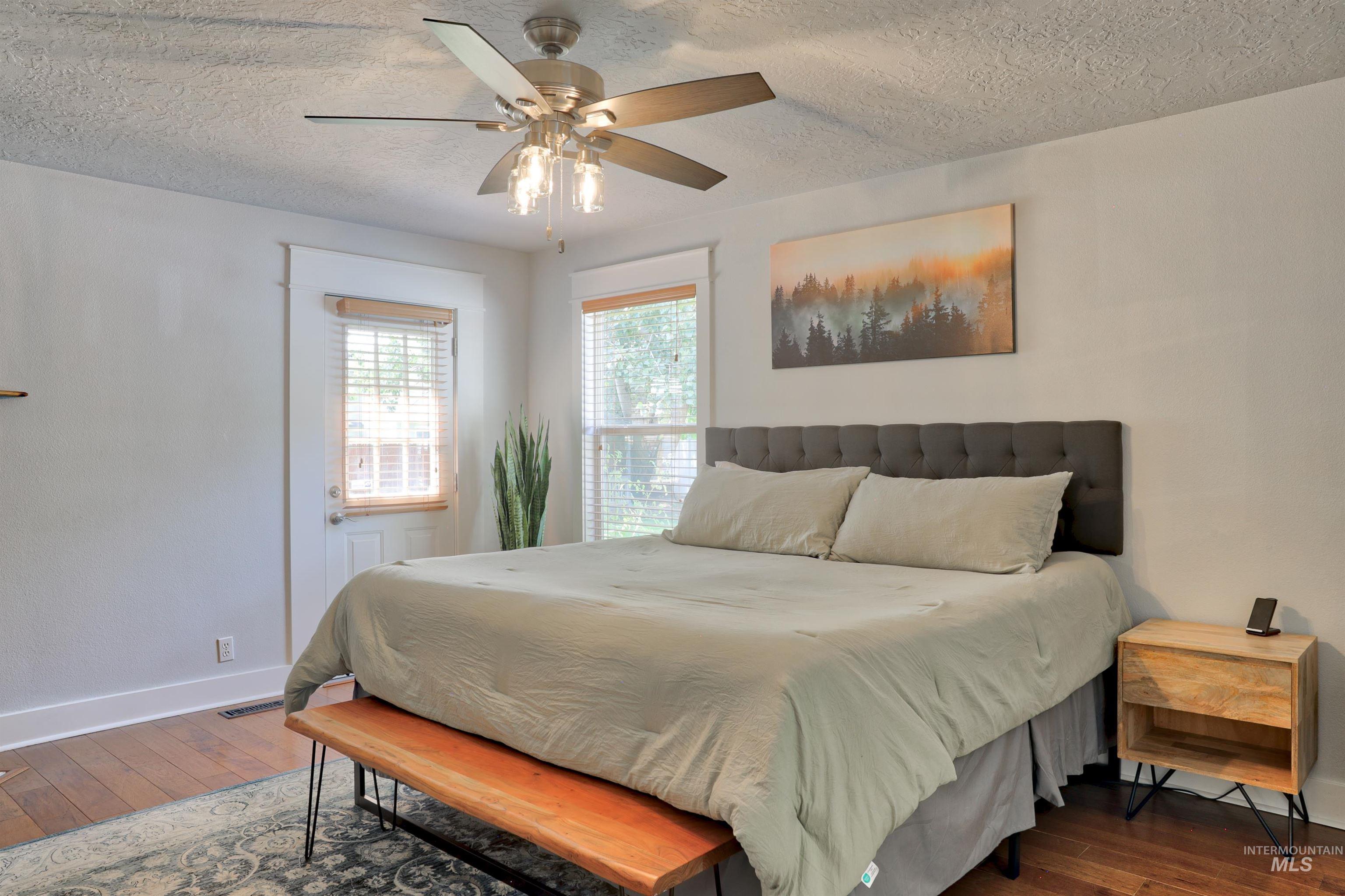 Bedroom featuring a textured ceiling, wood-type flooring, and a ceiling fan