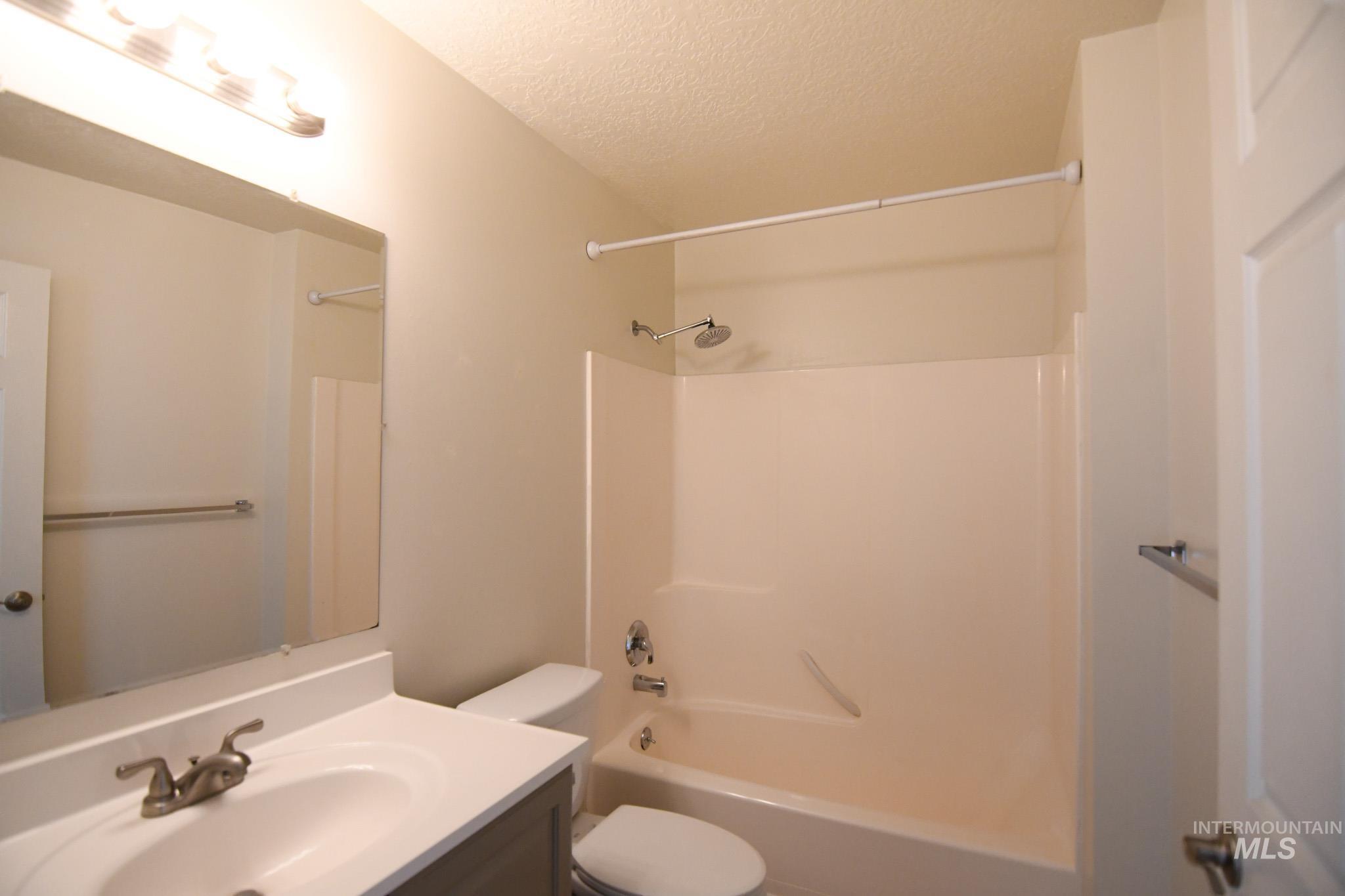 Full bath with a textured ceiling, vanity, and shower / bath combination