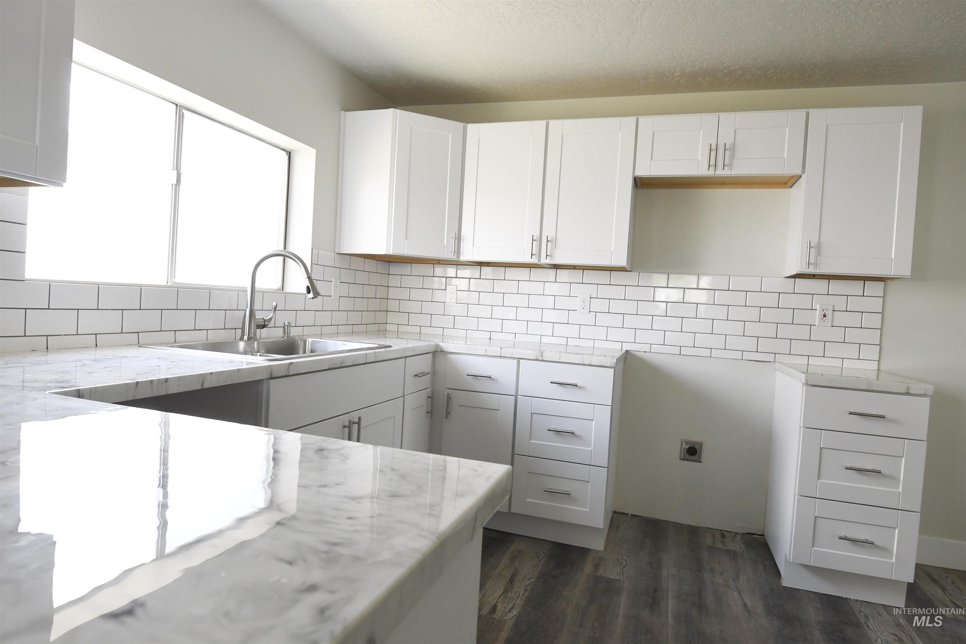 Kitchen featuring white cabinetry, dark wood-style floors, backsplash, and light stone counters