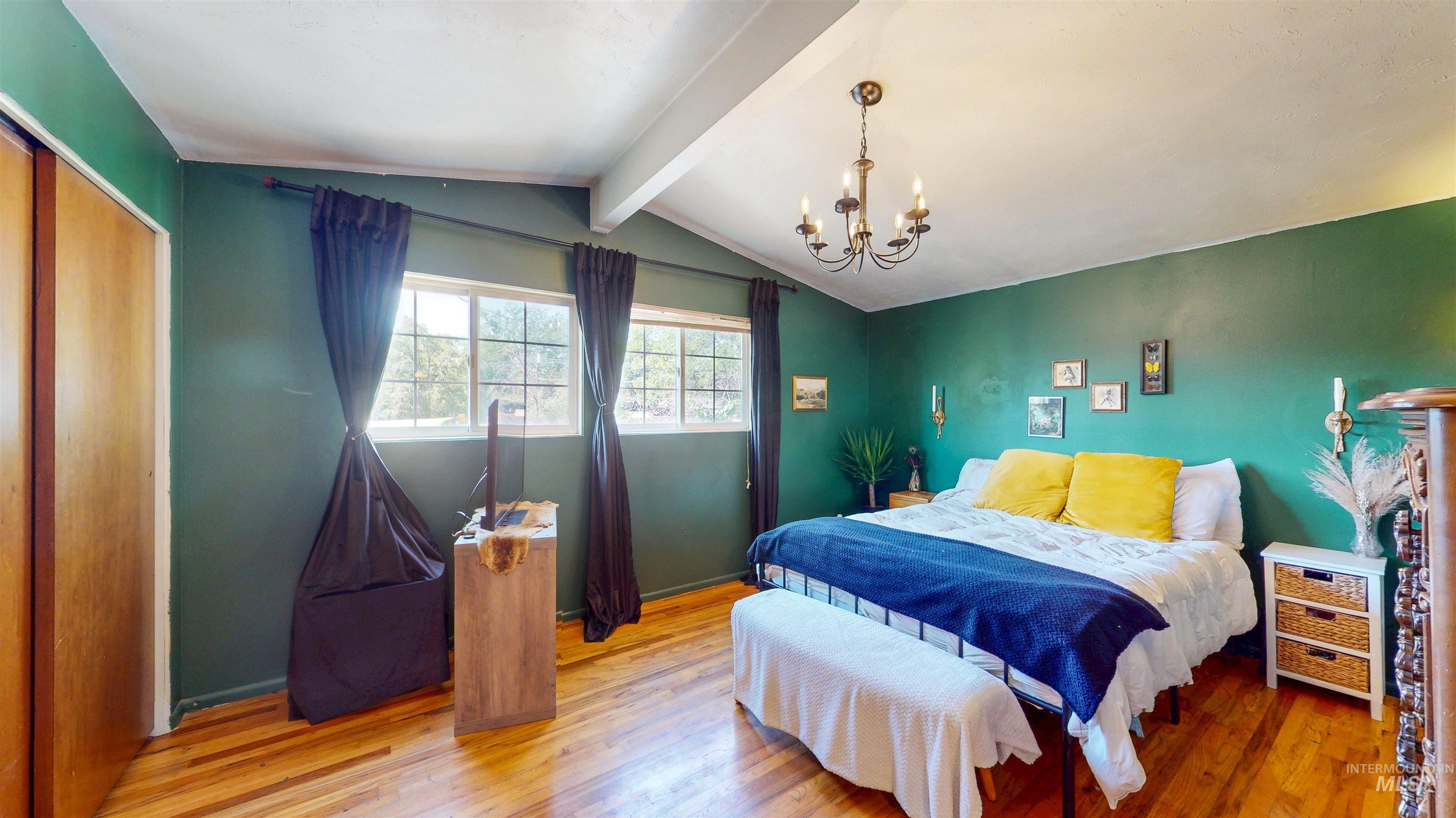 Bedroom with wood finished floors, a chandelier, and a closet