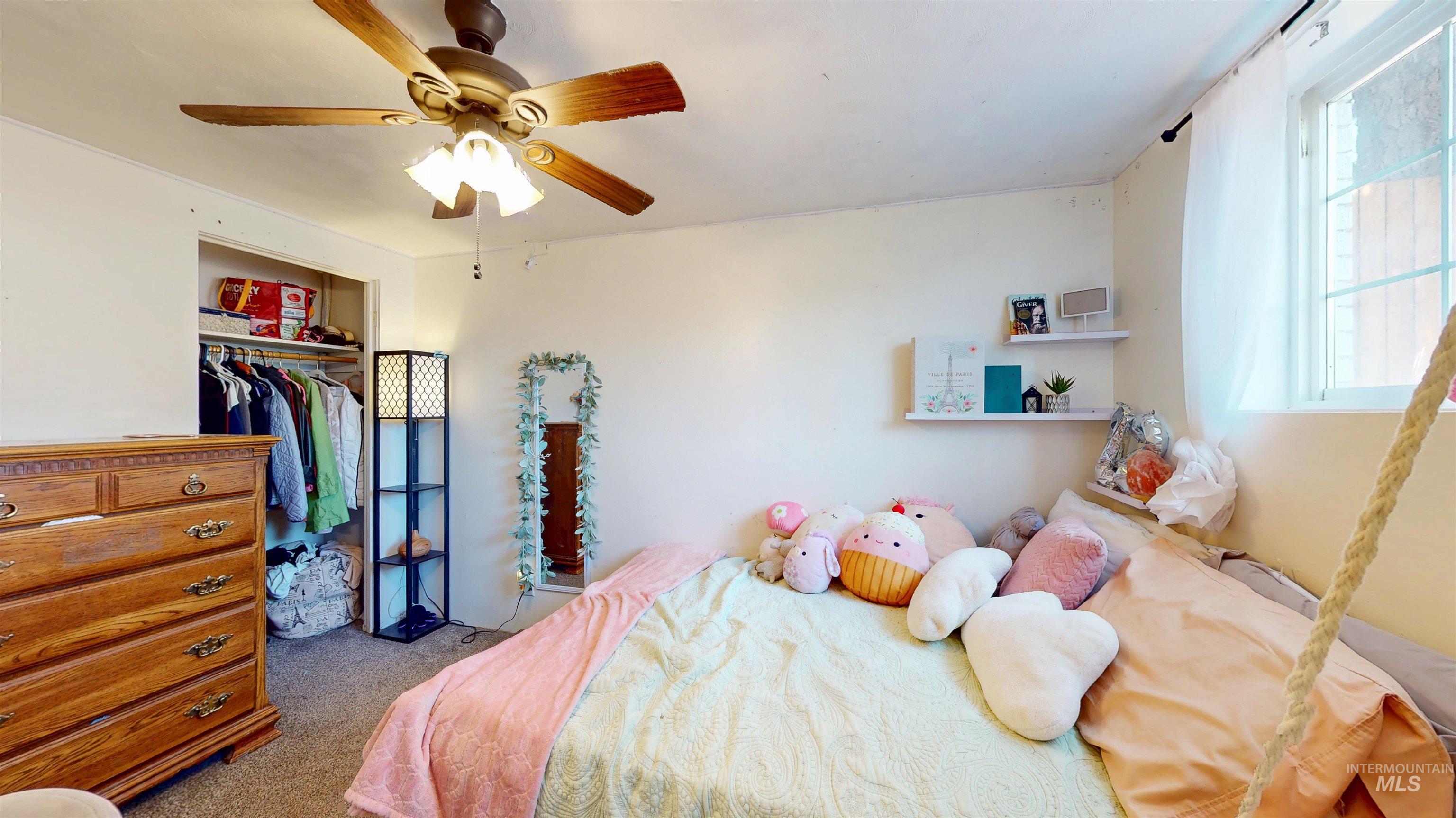 Carpeted bedroom featuring multiple windows, ceiling fan, and a closet